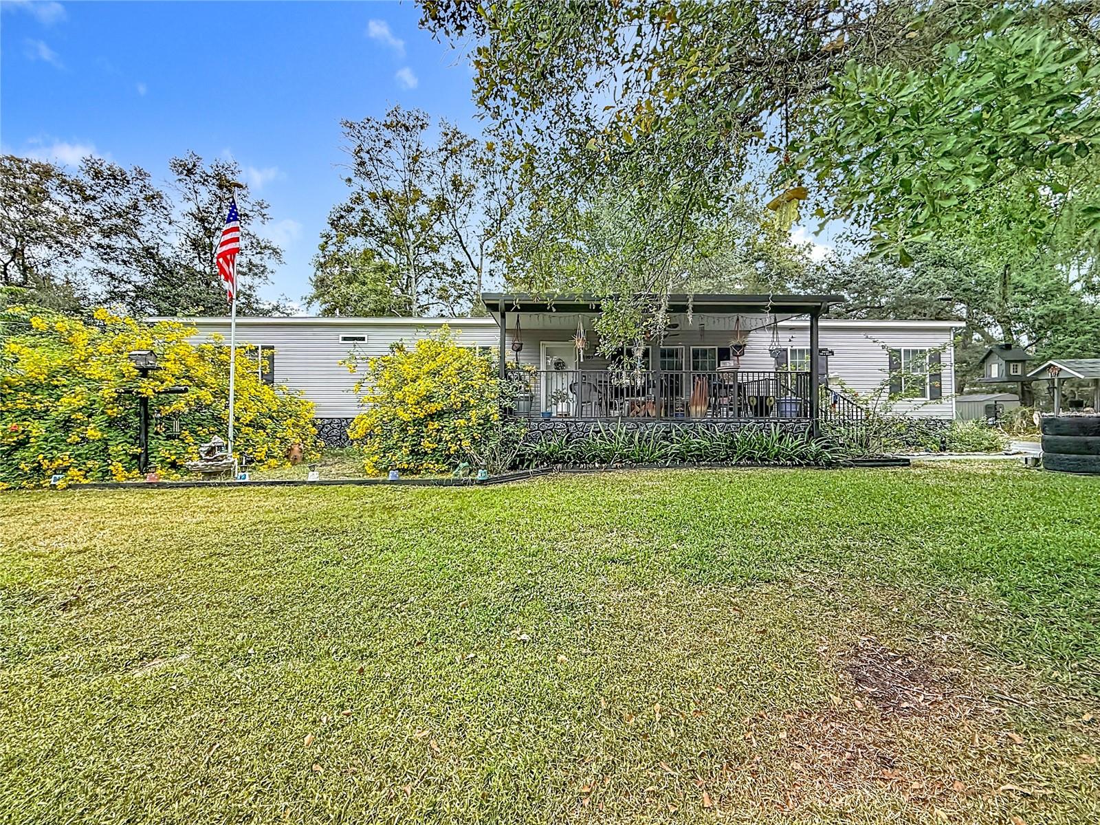 You’ll be impressed as soon as you approach this well-maintained 3-bedroom mobile home, plus a huge office and 3 full bathrooms. Built in 2019, this residence sits on just over half an acre, offering privacy and plenty of space to enjoy. The property is fully fenced, providing security and peace of mind. A gated entry leads to the blacktop driveway and carport, which features an extended parking area for additional vehicles. The inviting 12x22 front porch welcomes you to the home and sets the tone for what’s inside. Step inside to an open-floor concept with a split bedroom plan, ideal for both entertaining and everyday living. The eat-in kitchen is a chef’s dream, featuring ample space, a center island with bar seating, extra cabinetry, and a huge walk-in pantry for all your storage needs. The roomy master bedroom includes a luxurious master bath with a garden tub, dual sinks, a shower equipped with three grab bars, and a massive walk-in closet. The office shares a Jack and Jill bathroom with the spacious second bedroom, and the third bedroom has convenient access to the third full bath just outside its door. This home is finished throughout with drywall, crown molding, and chair rails, adding elegance and durability. The dedicated laundry room comes complete with a washer and dryer for your convenience. Enjoy the beautiful Florida weather from the 14x26 screened porch with tile floors, overlooking your very own tropical oasis garden. The garden includes banana trees, papaya trees, a greenhouse, and grow boxes—all with a built-in watering system to keep everything lush and vibrant. Additional features include leaf guard gutters with transferable warranty, 8 drains that lead to the draining ditch, a generator hookup with portable generator included. The 12x24 shed is equipped with electricity, workbenches and an outdoor sink for easy clean-up and projects. This exceptional mobile home seamlessly blends comfort, convenience, and style with plenty of indoor and outdoor living space. Whether you’re looking to relax on your screened porch, garden in your tropical oasis, or work from home in your spacious office, this property offers something for everyone.