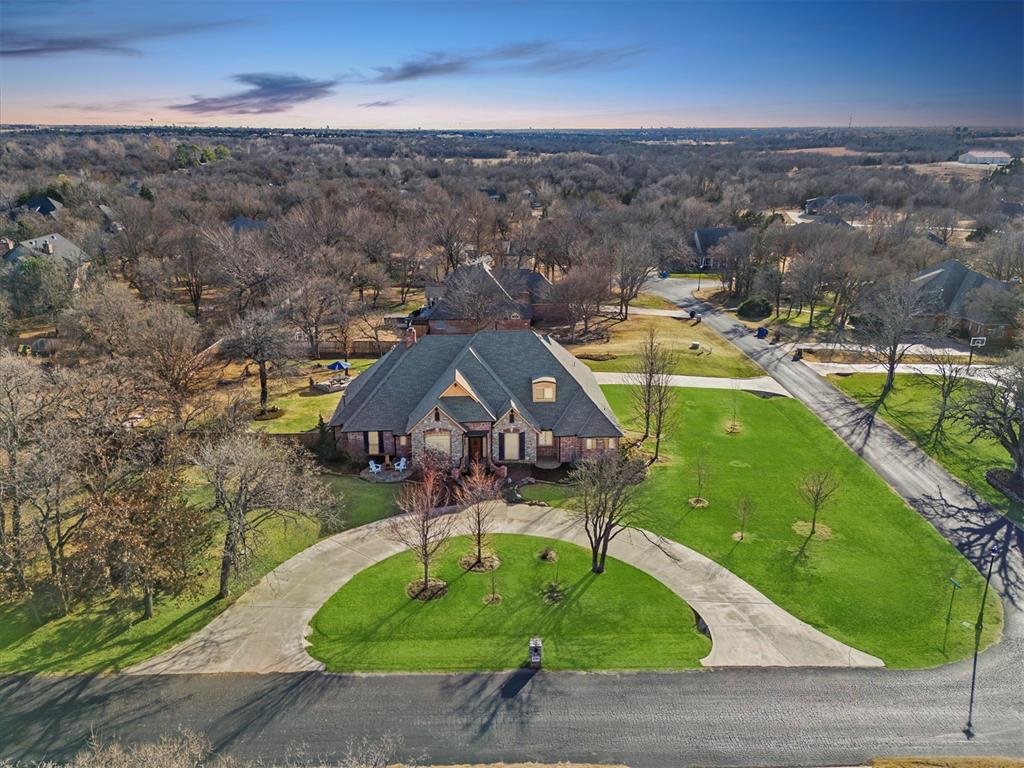 Nestled on treed, lushly landscaped acreage in the highly sought-after Deer Creek School District, this stunning home offers privacy, luxury, and exceptional spaces for everyday living and entertaining. A circular drive welcomes you to this beautifully appointed residence featuring a great room with wood flooring, a stacked-stone masonry fireplace, vaulted ceilings, and exposed beams that create warmth and architectural charm. The home offers two distinct dining spaces, ideal for both formal gatherings & casual meals. The primary suite serves as a serene sanctuary, complete with private patio access, two closets, and a spa-like bath showcasing separate vanities &  a luxurious rain-head shower. Two additional downstairs ensuite bedrooms offer ideal accommodations for guests or family, while a fourth bedroom is located upstairs. A study with a full wall of built-in bookcases provides a functional workspace. An additional work space includes built-in file drawers and ample storage. The enchanting backyard is a true retreat, overlooking a sparkling pool & park-like grounds with multiple patios, perfect for hosting gatherings or enjoying peaceful moments outdoors. A professionally designed landscape includes a flagstone patio & a fully screened sunroom with a masonry wood-burning fireplace, & electric hurricane shutters. Upstairs, enjoy a theater room complete with wet bar, wine fridge, projection setup, & pre-wired surround sound. A heated & cooled flex space provides endless possibilities for a hobby area, or seasonal storage. The home is finished with upscale details throughout, including a commercial-grade iron chandelier, custom cabinetry, pantry, and a dry bar/buffet area. The utility room features a sink & more storage. Additional features include an outdoor storm shelter accommodating 8–10.  The owners expanded the home with a second level and completed a remodel in 2011. Recent updates include a new roof and guttering installed in January 2026.  Welcome Home.