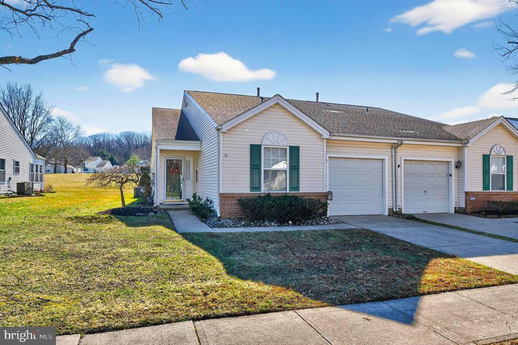 Tucked along peaceful open space in Holiday Village East, this Rosemont end-unit patio home offers nearly 1,600 square feet of bright, comfortable living in one of the community’s most desirable locations.Inside, the home opens into the foyer and a spacious layout designed for both everyday living and entertaining. The living and dining rooms flow together easily, creating a welcoming space.Toward the back of the home, the eat-in kitchen features classic cabinetry and Corian  countertops. and a convenient pantry. Just beyond, the kitchen opens into the four-season sunroom/family room, a favorite feature of the Rosemont model. With walls of windows and views of the open green space behind the home, it’s the perfect place to relax year-round.Step outside to the rear patio, where you can enjoy quiet mornings, outdoor dining, or weekend gatherings.The primary bedroom suite is privately positioned at the rear of the home and includes a walk-in closet and an ensuite bath with a walk-in shower and built-in seating. A second bedroom at the front of the home offers a comfortable space for guests or a home office and sits near the full hall bath.Additional features include a laundry room with washer and dryer and direct access to the one-car garage, which also provides pull-down attic storage. Residents of Holiday Village East, a vibrant 55+ community, enjoy amenities including lawn care, snow removal to the door, leaf removal, a seasonal outdoor pool, clubhouse, tennis, bocce, and pickleball courts, plus a full calendar of social activities.  Conveniently located near shopping, dining, medical facilities, and major roadways, with easy access to Philadelphia and the Jersey Shore. Come see why so many love calling Holiday Village East home.