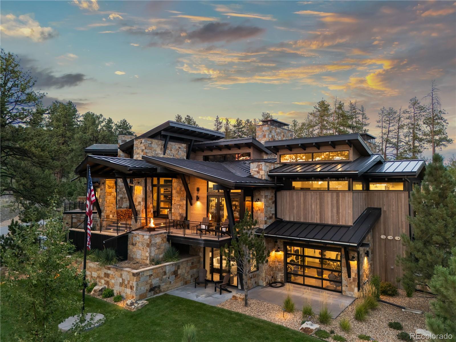From the moment you arrive, this modern one-of-a-kind residence, situated on more than 6.5 acres, makes an unforgettable impression. With bold architecture that’s as visually stunning as its Colorado backdrop, this 6 bedroom | 8 bathroom home with garage parking for 9+ vehicles is truly unmatched in the coveted Village at Castle Pines community. Upon entry, the great room features soaring ceilings, wide plank hardwood floors, a gas fireplace, and walls of windows that bring the outside in. Huge sliding glass doors open to the covered outdoor kitchen, patio, and flat yard, creating a perfect setting for entertaining underneath starry skies. The interior open concept kitchen showcases custom cabinets, Dacor and Miele appliances, and an oversized waterfall edge island, while a nearby wet bar and wine wall make year-round entertaining seamless. The lux primary suite includes vaulted ceilings, a gas fireplace, patio access, and an en suite bathroom complete with heated floors, dual vanities, a soaking tub, and oversized steam shower, while a contemporary office opens to a mountain-view deck and a main floor guest suite features vaulted ceilings, deck access, and an en suite bathroom. Two upper level en suite bedrooms each offer private balconies. Downstairs, the family | rec room includes a projection screen, linear fireplace, wet bar, and game area, while 2 en suite bedrooms, a workout room, and uniquely unparalleled safe room complete this level. An elevator provides convenient access throughout the home. An added bonus, the impressive adjacent car collector’s garage provides multiple vehicle bays and an additional entertaining area with kitchenette, 2 half bathrooms, and ample storage, creating a remarkable setting for showcasing an automotive collection or hosting parties. Built with exceptional craftsmanship and enduring quality, this is a rare property: where every season brings a new opportunity to gather, reflect, celebrate, and create lasting memories.