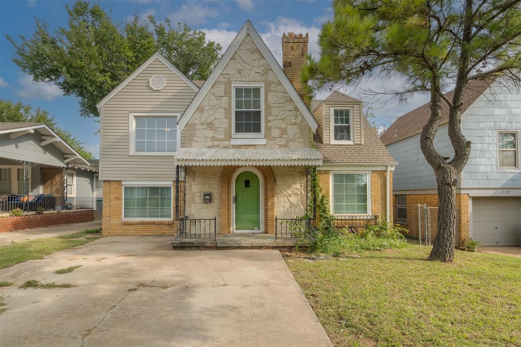 With its steep pitched gable, arched front door, ornate chimney, and mix of natural materials, this delightful Tudor revival style home in Putnam Heights feels like it was ripped from the pages of a storybook. The covered front porch and brick arched entry provide a welcoming invitation inside. The main living area is well proportioned and bright with windows gracing the east and south walls. The style perfectly blends comfortable classic historic character with more transitional design elements. The open staircase adds architectural interest. The attractive arched pass-throughs carry the Tudor theme throughout. The living area opens nicely to a formal dining room with exquisite, corner built-in cabinets with leaded glass doors and cafe-style shutters. The kitchen is loaded with cabinet and counter space and includes updated stainless steel gas stove, refrigerator, and dishwasher. On the opposite side of the main living room is a casual, second living space which would serve as a lovely reading or media room. It includes an attached, updated full bathroom with corner, low-entry shower and laundry area. Up the first flight of stairs, you'll find another full bathroom with stunning, original black and white tile, as well as a well-lit and sizable guest bedroom. On up from there, you will find the primary bedroom which attaches to two very practical adjacent rooms. One works beautifully as a home office, while the other would function well as an oversized dressing room. The storage options abound. The backyard feels infinite with shaded areas near the home and sun-soaked areas towards the back to live out all of your gardening dreams. The driveway is two cars wide for off-street parking. The access to all of your favorite arts, dining, and shopping spots, as well as a front-row parade view, make the location a dream.