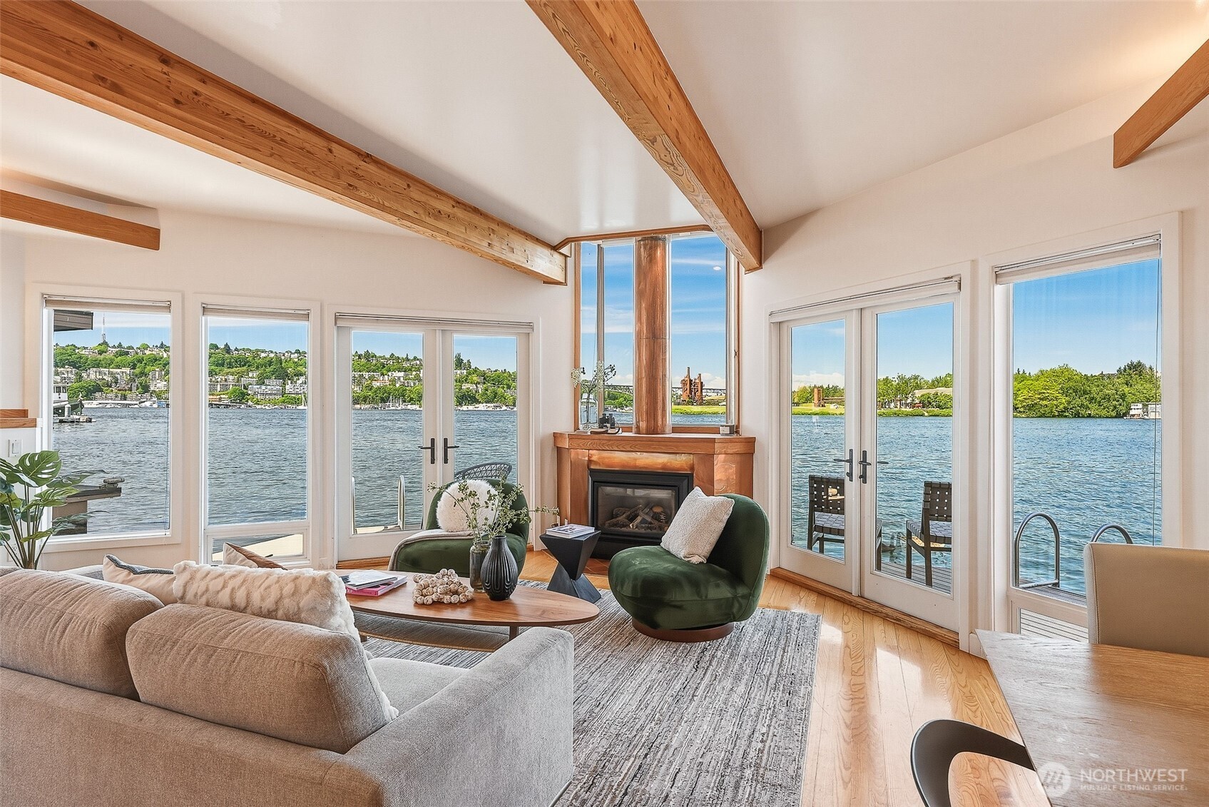 RARE front-row west-facing Lake Union floating home with oversized deep-water moorage. Exceptional 3-bedroom + office, 2.25-bath offering sun-drenched, unobstructed panoramic views of the water, city skyline, and mountains, framed by expansive windows. The open-concept layout flows effortlessly from the inviting living spaces to the waterside decks, creating the perfect setting for entertaining, relaxing, or launching your next water adventure right from your doorstep. The kitchen features clean lines, abundant cabinetry, and a seamless connection to the main living and dining areas, while curated design details including a striking copper fireplace, warm wood finishes, and vaulted open-beam ceilings add warmth and sophistication throughout. It also includes a versatile main-floor office/den/storage room. Perched above the main living spaces, the primary suite offers dramatic vaulted ceilings, expansive views, and dual private balconies, plus a spa-inspired bath, a spacious walk-in closet, and a built-in desk area. The upper level also includes two secondary bedrooms, a shared 3/4 bath, laundry, a sun-filled garden nook, and access to the rooftop deck ready for your vision to create your dream entertaining space. Gated, secure Roanoke Reef Dock, 45’+ moorage plus 2nd smaller moorage, secure garage parking w/EV & storage room, plus additional residence parking. Vibrant Eastlake neighborhood. Unique opportunity at a historically low price!