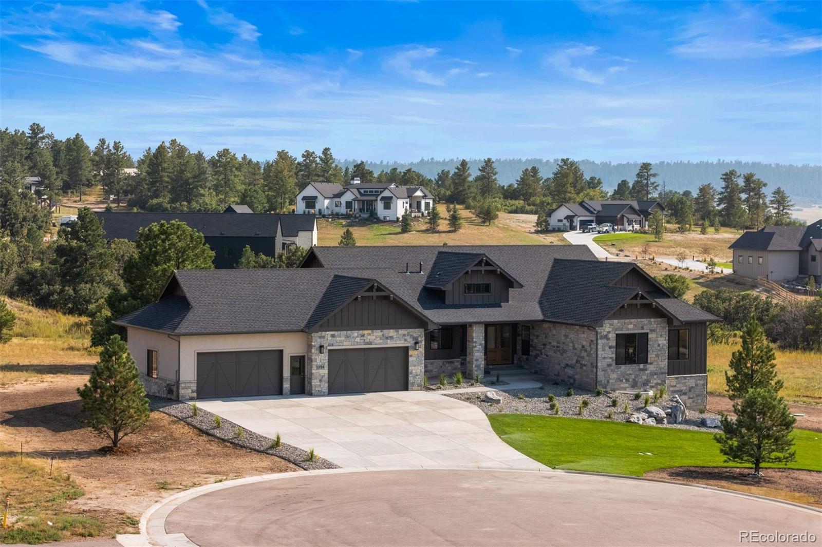 Now complete, this sprawling brand-new ranch blends presence and livability, designed with perspective, grounded in the landscape, and finished with intention in every detail. Set on two private acres in Franktown’s gated Arrowpoint Estates, where private trails wind through the pines and Pikes Peak lingers on the horizon. A defining material, Texas Lueders Limestone makes a strong architectural statement inside and out. Step into the great room, where vaulted ceilings with beams, white oak floors, and a 48-inch limestone fireplace create a grounded, welcoming centerpiece. Open the sliding doors and the room spills onto a vaulted covered deck, perfectly placed for evenings lit by Colorado sunsets. Built for serious cooking, the kitchen delivers with a 48-inch Wolf range, Sub-Zero refrigeration, two Asko dishwashers, and when the party’s on, the back kitchen picks up the slack with extra prep space and a walk-in pantry to keep the main stage spotless. The primary suite features direct access to the deck, a zero-threshold shower, freestanding tub, marble-topped vanities, and a walk-in closet anchored by a center island. Downstairs, the walkout basement extends the living space with a 60-inch linear fireplace, a wet bar, covered patio with pergola, and a workout room. The oversized four-car garage features enough depth for an extended-bed truck. Built by Gladstone Custom Homes—known for blending craftsmanship with livable luxury—this property delivers both presence and permanence. Tucked into a quiet corner of Franktown, just minutes from Castle Rock, Parker, and I-25, the location balances everyday access with Colorado’s beauty.