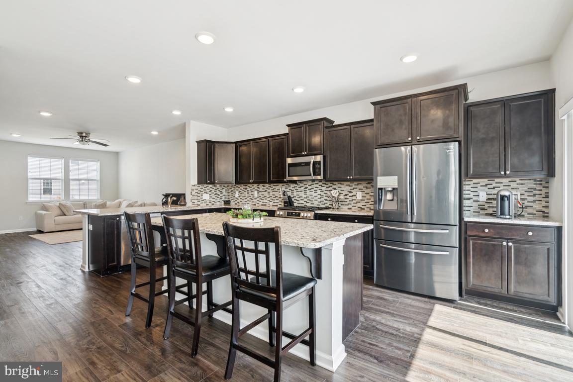 Welcome to 16 Naples Way — a beautifully maintained and thoughtfully designed townhome where modern luxury meets smart functionality across three spacious levels. Featuring three Bedrooms, three full Baths, and a convenient half Bath, this home offers exceptional flexibility to fit a variety of lifestyles. The entry level welcomes you with a bright and versatile Family Room complete with a full Bath, generous closet space, and sliding doors that open to the backyard—ideal for a Guest Suite, Home Office, or even a fourth Bedroom. Elegant waterproof vinyl flooring carries effortlessly from the entry through the main Living Level, blending modern design with lasting durability. Upstairs, the main Living Area shines with an open-concept layout and a stunning Kitchen as its centerpiece. A large granite island, mosaic tile backsplash, upgraded lighting, and premium cabinetry create a space that’s as functional as it is beautiful. Custom blinds accent each window, adding warmth and sophistication. Step out onto the private deck overlooking lush landscaping—with no townhomes or apartment buildings behind—your own peaceful retreat. The top floor features the home’s sleeping quarters and a convenient Laundry Area. The Primary Suite offers a walk-in closet and a private Ensuite Bath, creating a comfortable and stylish retreat. Two additional Bedrooms share a well-appointed hall Bath. Designed with smart living in mind, this home was professionally wired for home automation during construction, allowing for seamless integration of your favorite smart devices. Additional highlights include newer carpeting and paint, recessed lighting throughout, and thoughtful design elements that create a warm, inviting atmosphere. The home also features an attached Garage pre-wired for a car charger and enjoys a prime location within the community near guest parking. Combining beauty, technology, and versatility, 16 Naples Way offers a timeless design tailored for today’s modern lifestyle.