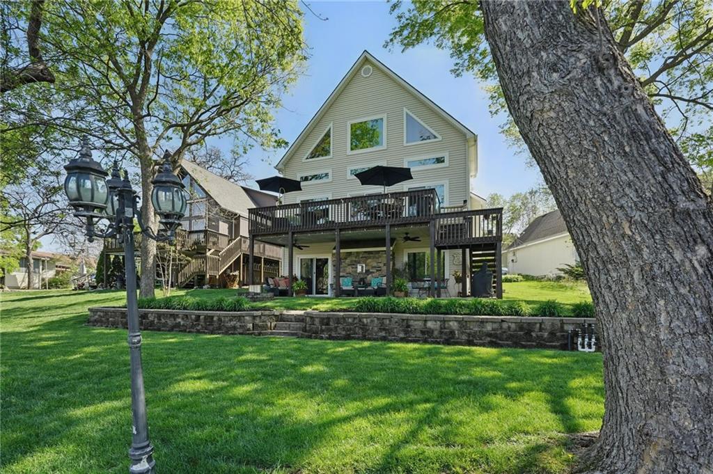 Rare opportunity for an updated/upgraded 1.5 story lakefront home on wide cove, with private dock! Low maintenance vinyl siding, stone trim, 3 car wide, level drive & 2 car garage! Main level living at its finest! Wood floor from entry through great room, dining, office! 20'+ vaulted ceiling, large windows with stunning views of the lake! Great room has gas fireplace with stone surround & wood mantle, slider opens to deck that runs full width of home, offering expanded entertaining space, stairs down to patio below, backyard and short distance to dock! Large dining area shares the lake views & vaulted ceiling. Kitchen is open to great room with granite counters, s/s appliances, tons of cabinets & walk-in pantry! Private primary suite is huge, vaulted ceiling & long window seat with hidden storage. Private bath has jetted tub, with shower, dbl vanity, tile floor, private room for toilet & great walk-in closet! Laundry just across the hall. Great office & 1/2 bath complete main level. 2nd floor is a private suite with large loft/living area, full bath with tiled shower & bedroom with large walk-in closet! Lower level has huge family room with 2nd gas fireplace with stone surround & wood mantle, wet bar with tons of storage & counter space, floating shelves, LVP flooring ideal for coming in from the lake! Slider out to patio under entire deck with ceiling, offering dry outdoor entertaining space with stone firepit. Gorgeous lush lawn, mature/maintained trees, just a couple steps down and out to private dock! Lower level also has 2 large bedrooms, full bath, bonus 2nd office space with great closet storage. HUGE unfinished storage space reveals engineered floor joists, tankless water heater, high efficiency furnace. Deck is 30 x 11, with same sized patio below!