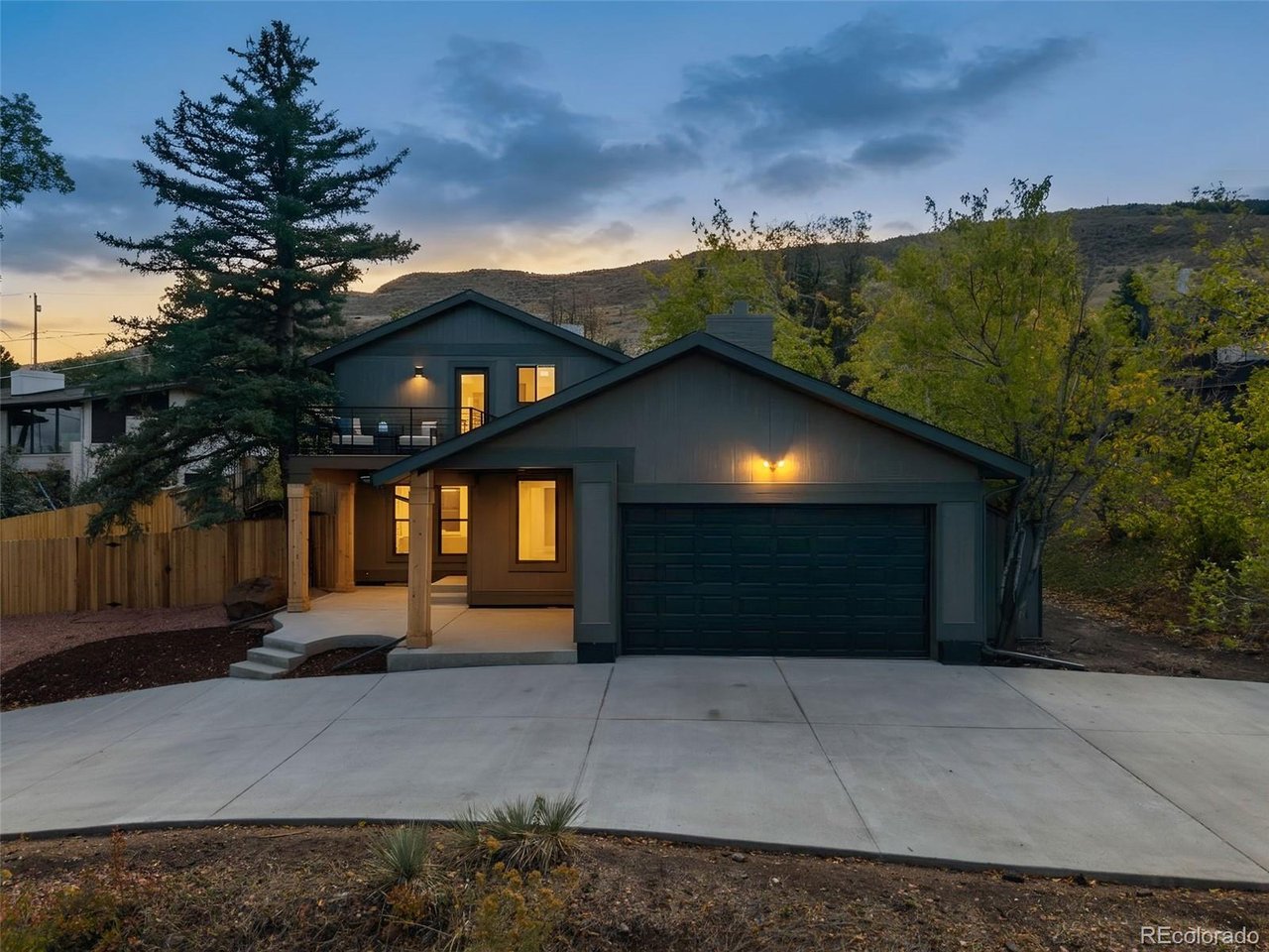 Situated in Golden's desirable Applewood neighborhood, this exceptional 5-bedroom, 5-bathroom home has been transformed with stunning finishes, modern design, and attention to detail throughout. The home boasts soaring ceilings, expansive windows, sprawling timeless floors, and an open floor plan filled with natural light. The living area showcases vaulted wood ceilings, a striking floor-to-ceiling stone fireplace, and architectural details that add warmth and character. A staircase with modern railings add to the home's distinctive design.The gorgeous kitchen is sure to impress with Taj Mahal quartzite countertops, custom cabinetry, an oversized eat-in island, stainless steel appliances, and designer lighting. Warm wood tones, rich finishes, and abundant cabinet and counter space make this kitchen both stylish and functional. The open layout connects the kitchen, dining, and living areas, creating an inviting atmosphere for everyday living and entertaining.The main level offers a bedroom and 3/4 bathroom, providing a convenient option for guests. Upstairs, the stunning primary suite is a private retreat with a cozy fireplace, beautifully finished ensuite bathroom, and a private deck with scenic views.The completely remodeled basement is perfect for entertaining, with an impressive full wet bar with sink, dedicated theater area, and plenty of room to gather. One additional bedroom with its own ensuite bathroom, provide comfortable accommodations for guests. The outdoor spaces includes decks, mature trees, and inviting areas to relax while enjoying Colorado's beautiful weather. Located in the established Applewood neighborhood, this home offers beautiful surroundings with convenient access to downtown Golden, the foothills, hiking and biking trails, shopping, dining, and Denver. With its remarkable design, quality craftsmanship, and thoughtfully selected finishes, this is a truly special property that stands apart from the ordinary.