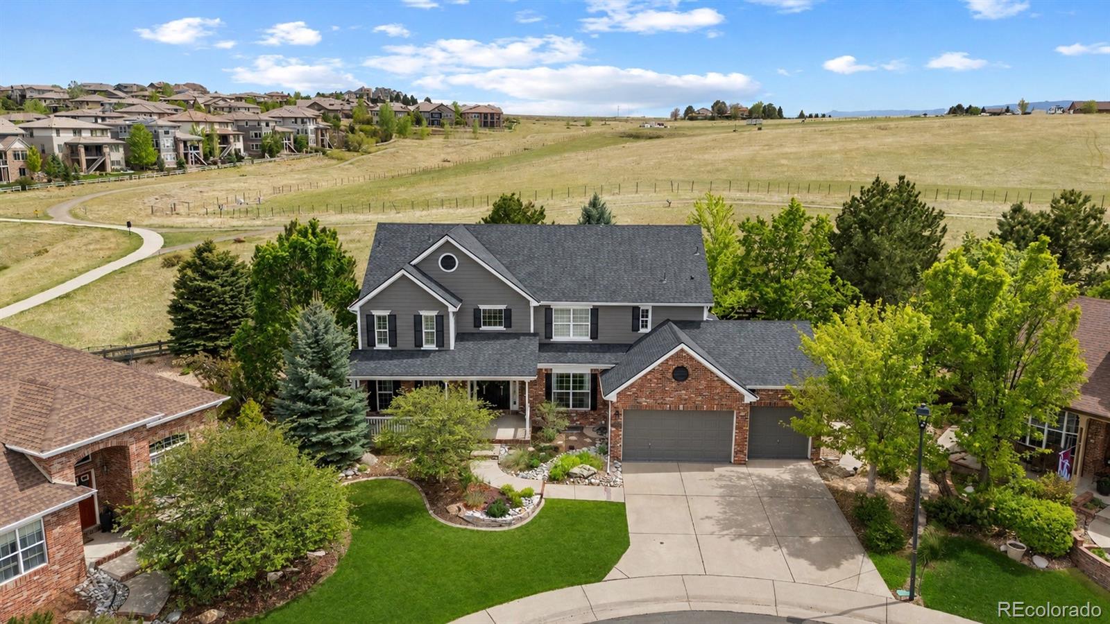 Tucked at the end of a peaceful cul-de-sac in Highlands Ranch and backing to open space, 10660 Weathersfield Court offers the perfect blend of luxury, comfort, and everyday functionality. Thoughtfully updated throughout, this home combines refined finishes with inviting living spaces designed for both entertaining and daily living. The main level is anchored by a stunning gourmet kitchen featuring premium Sub-Zero appliances, an oversized gas range with custom hood, dual dishwashers, refrigerator and freezer drawers, and an additional prep kitchen. A newly added built-in bench in the breakfast nook creates a gathering space, while updated designer light fixtures throughout the home bring a fresh, modern feel. The beautifully updated office with mountain views, complemented by spacious living and dining areas, a functional mudroom with custom storage, and an oversized laundry room with built-in workspace. Wide plank hardwood flooring, detailed millwork, and custom finishes add warmth and sophistication throughout the home. Upstairs, the primary suite feels like a private retreat with its own fireplace, spa-inspired bathroom, freestanding soaking tub, and custom walk-in closet. Secondary bedrooms are generously sized, including a fully updated ensuite bathroom and additional remodeled bath spaces that have been tastefully redesigned with high-end finishes. The finished lower level was built for entertaining with a large recreation area, wet bar, wine storage, fitness space, guest bedroom, and bathroom ideal for visitors. Outdoor living is equally impressive with a heated covered patio, built-in grilling station, firepit, and beautifully landscaped backyard overlooking permanent open space. Enjoy direct access to miles of nearby trails, parks, and neighborhood amenities, all while benefiting from major recent improvements including a brand-new roof. This is a rare opportunity to own a truly turnkey home in one of Highlands Ranch’s most sought-after locations.