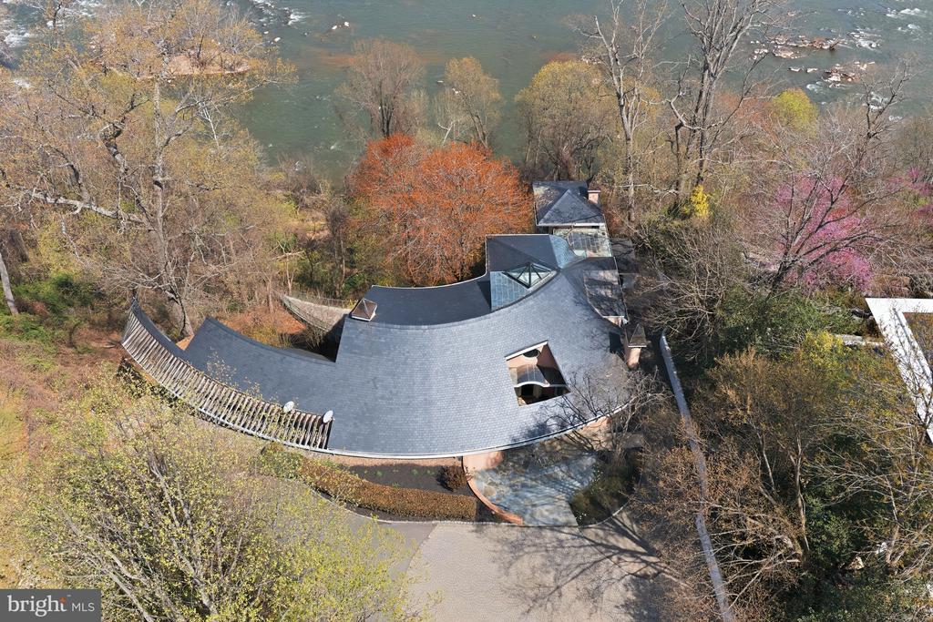 Welcome to Bella Vista, set along McLean’s Gold Coast. This extraordinary riverfront estate is perched on nearly 2.39 acres stretching directly to the water’s edge. The property commands sweeping views of the Potomac River and its dramatic cascading falls, creating a spectacular natural backdrop unlike any other in the region. A gently winding drive introduces the existing nearly 6,000-square-foot residence, thoughtfully designed to embrace the surrounding landscape. Expansive floor-to-ceiling windows across the main and upper levels capture the ever-changing river views, filling the home with natural light and connecting every major living space to the remarkable scenery beyond. The residence offers four generously sized bedrooms and five full baths, including a spacious main-level primary suite. Rich architectural elements include four fireplaces and a beautifully paneled library that creates warm, inviting spaces. Outdoors, an expansive terrace provides panoramic 180-degree views of the Potomac, offering a front-row seat to one of the area’s most captivating natural settings. Whether renovating the existing home or designing a custom riverfront masterpiece, this exceptional property presents a truly rare opportunity to create a private estate of enduring distinction. Located just minutes from Washington, D.C. and the business and shopping hub of Tysons Corner, the property offers effortless access to world-class dining, luxury retail at Tysons Corner Center, and premier outdoor recreation including Great Falls Park and Scott's Run Nature Preserve. Ronald Reagan Washington National Airport is just 15 minutes away, while the estate remains surrounded by some of McLean’s most prestigious estates.