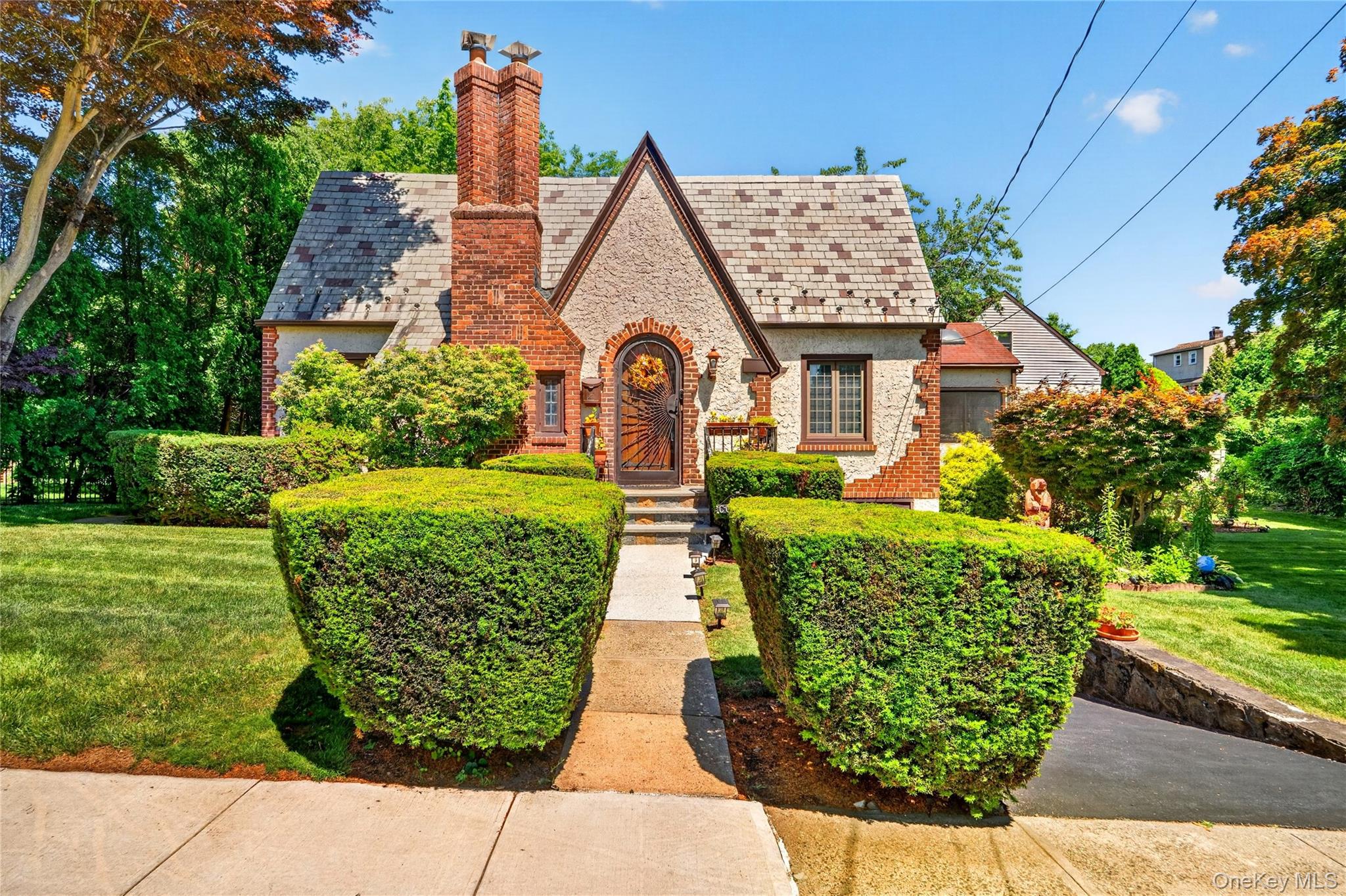 Charming Tudor-style home full of timeless character, ideally situated on an oversized lot in a desirable New Rochelle neighborhood. Featuring hardwood floors, a classic slate roof, central air, central vacuum, and beautiful architectural details throughout. The main level offers a spacious living room, formal dining room, kitchen with updated appliances, a versatile sitting room that can serve as a guest room or home office, a full bath, primary bedroom, and a stunning sunroom with panoramic views of the surrounding greenery. Upstairs you'll find two additional bedrooms, a full bath, and a large unfinished attic offering the potential to expand one of the bedrooms or create additional living space. The full basement with garage access provides endless possibilities for storage, recreation, or future finishing. Recent improvements include newer sunroom windows, regularly serviced HVAC, and a built-in 5-zone sprinkler system. Conveniently located near parks, playgrounds, sidewalks, shopping, dining, and both Pelham and New Rochelle Metro-North stations for an easy commute.