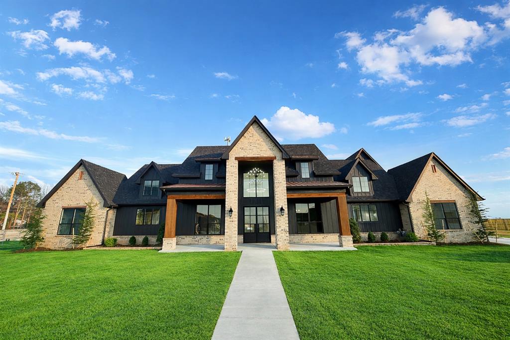 Welcome to this stunning custom built modern show stopper that perfectly blends timeless elegance with contemporary design. From the moment you arrive, the striking brick exterior, bold black accents, and warm wood beams create incredible curb appeal and a grand first impression. Step inside to soaring ceilings, abundant natural light, and an open concept floor plan designed for both everyday living and entertaining. The chef’s kitchen is a true showpiece featuring an oversized island, quartz countertops, custom cabinetry, designer lighting, and premium appliances all flowing seamlessly into the spacious living area with a beautiful stone fireplace and wood beam ceiling detail. The private primary suite is a retreat of its own, highlighted by a rare two-story master closet complete with custom builtins and a staircase leading to the upper level offering unmatched storage and boutique style organization. Upstairs and throughout the home, you’ll find thoughtfully designed spaces including:  A dedicated theater room with elevated platform seating area, perfect for movie nights and game days, designer staircase with custom iron railing, high-end finishes and lighting throughout, and spacious secondary bedrooms and bathrooms. Outdoor living is just as impressive with a fully equipped covered patio featuring a brick outdoor kitchen, grill station, granite countertops, fireplace, wood paneled ceiling, and ample space for entertaining year round. This home offers luxury, functionality, and unforgettable design ideal for both entertaining and comfortable living.