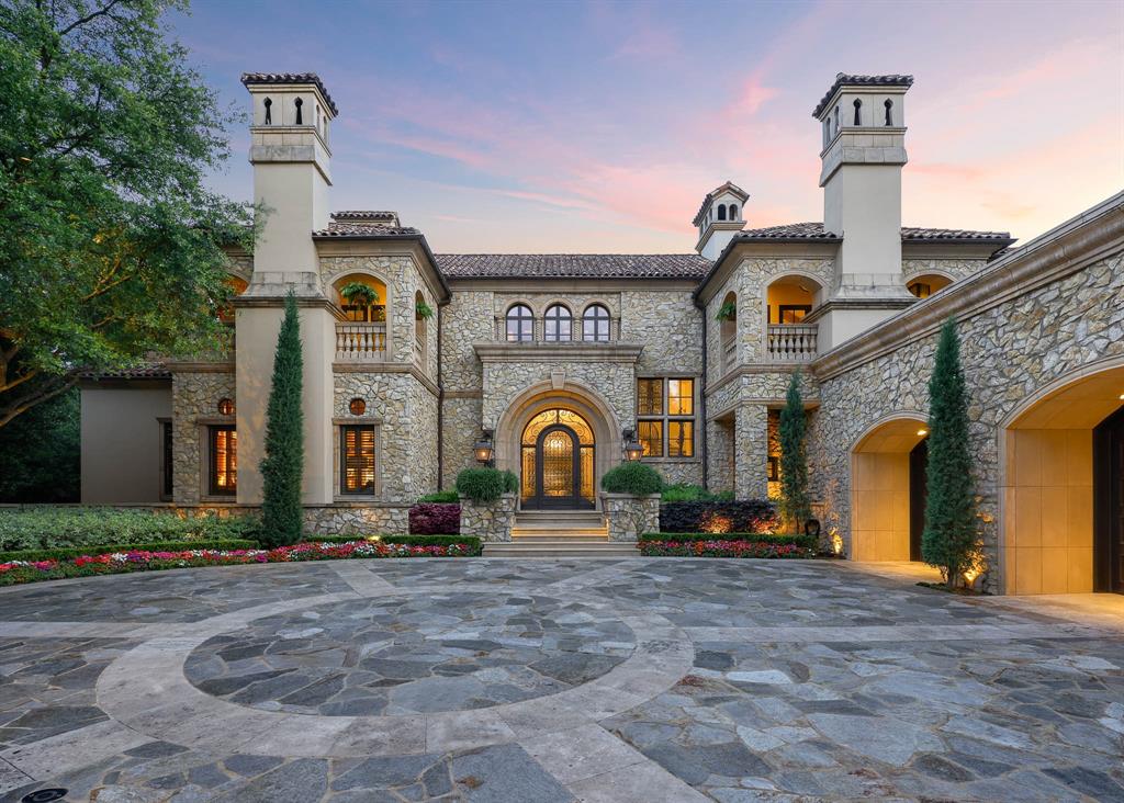 Rising behind a circle drive and flanked by Mediterranean cypress trees, 15 Robledo Drive evokes the timeless romance of a European villa. Within the gates of Los Arboles, Preston Hollow’s most exclusive enclave, the estate reveals itself like a scene from the Tuscan countryside — limestone cladding, ironwork arches, and a harmony of sunlit spaces. Originally designed by Robert Trown and recently updated by J.R. Cattington Interiors, the home balances Old World character with modern livability. Reclaimed oak floors and hand-hewn beams add texture, while arched openings and generous ceiling heights guide you from one light-filled room to the next. A richly paneled library, formal living and dining spaces, and a butler’s pantry lend themselves equally to both intimate moments and grand entertaining. The kitchen shines with custom millwork and veined stone, flowing into a cheerful breakfast nook, relaxed family lounge, and study. Across the home, eight fireplaces weave a unifying thread of warmth and elegance. The main-level primary suite feels like a private wing, complete with dual baths and boutique-style closets. Upstairs, two guest suites rival luxury hotels, each with its own fireplace and balcony. A fitness room, bonus space, and ample storage complete the second floor. Outdoors, the estate unfolds with equal composition and care: a waterfall-fed pool, lush gardens, pavilion, putting green, and a loggia with fireplace and kitchen — coming together to make everyday living feel exceptional. Control4 home automation, dual garages, and a private elevator ensure the home lives as effortlessly as it looks. 15 Robledo Drive offers a rarity in today's market: an updated home that preserves the soul of a classic estate.