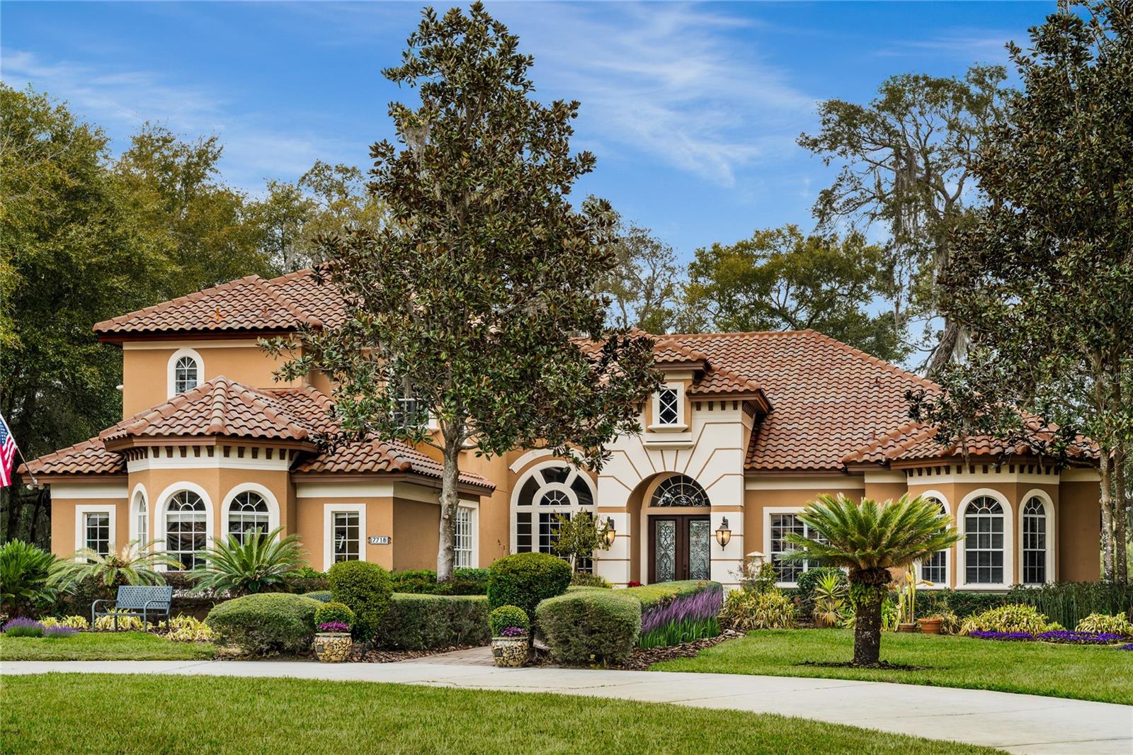 Welcome to the finest expression of luxury urban living, where Mediterranean elegance meets modern sophistication in a residence worthy of the pages of Architectural Digest. Perfectly positioned on a pristine one-acre, pond-front corner homesite within the exclusive Lake Markham Preserve, this award-winning custom estate showcases a Parade of Homes floor plan crafted by Waterford and offers over 5,000 square feet of impeccably designed living space. A circular driveway and striking transitional exterior create a grand arrival, highlighted by arched windows and an ornate roofline that set this home apart. Solid mahogany leaded glass doors open to a refined foyer where formal living and dining spaces unfold, enhanced by elegant ceiling details, a serving bar, abundant natural light, and sweeping views of the resort-style pool. At the heart of the home lies a stunning circular gourmet kitchen designed for both entertaining and everyday living. A massive ebony working island anchors the space, complemented by exotic granite, glazed cherry custom cabinetry with illuminated glass fronts, decorative backsplash, and a premier Wolf and Sub-Zero appliance package, including a five-burner gas range and ice maker. A fully equipped butler’s pantry adds convenience and sophistication. The kitchen flows seamlessly into the expansive family gathering area, where a cozy fireplace, inset media wall, dramatic ceilings, and walls of windows and doors invite indoor-outdoor living. The luxurious primary suite offers Brazilian hardwood flooring, coffered ceilings with crown molding, a lighted art niche, and a comfortable sitting area. The spa-inspired bath features a Cleopatra soaking tub framed by plantation-shuttered windows, a beautifully designed Roman walk-in shower, and separate vanities, creating a tranquil retreat. A versatile first-floor in-law or guest suite with kitchenette and bar provides exceptional flexibility and may also serve as a bonus or entertainment room. Upstairs, a tri-level design offers four generously sized bedrooms thoughtfully positioned across both wings of the home for privacy and comfort. The laundry room is equally well-appointed, offering abundant cabinetry, folding space, and utility sink for convenience. Outdoor living is equally spectacular, expansive pavered terraces and decorative columns frame a newly designed summer kitchen finished with stacked stone, granite counters, and ample storage. The oversized pool is surrounded by lush, flowering gardens, creating a private resort atmosphere that blends seamlessly with the tranquil waterfront backdrop. Garden enthusiasts will appreciate the meticulously maintained grounds featuring a variety of fruiting and exotic plants, including elderberry, avocado, olive, lemon, lime, and blueberry bushes. Every inch of the landscape reflects pride of ownership. This distinguished custom home has been meticulously maintained by vigilant owners, with over $200,000 invested in upgrades and ongoing care, offering peace of mind and true move-in readiness. Lake Markham Preserve is a guard-gated enclave of just sixty unique residences nestled within the sought-after Markham Woods Corridor. Residents enjoy proximity to a pristine freshwater ski lake, scenic preserves, parks, golf courses, nature trails, sports facilities, charming historic downtown Sanford, and Seminole County’s exemplary schools. This remarkable residence delivers elegance, comfort, and lifestyle beyond expectation.