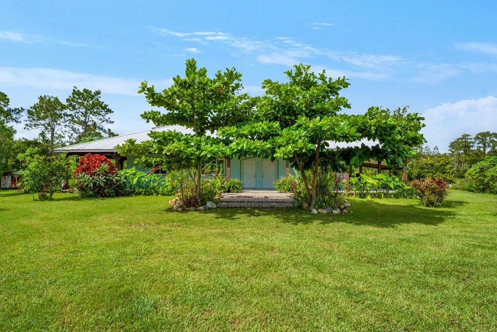 Welcome to Your Florida Country Retreat!
Discover the perfect blend of comfort, style, and freedom in this stunning 2-bedroom, 2-bath home with an office/den that can easily convert into a third bedroom. Offering over 1,700 sq. ft. of thoughtfully designed living space, this home invites you to experience the best of Florida country living — with all the modern touches you love.  Step inside to find high 9’ ceilings throughout opening up to a cathedral ceiling in the great room, decorative fixtures, and high-end cork flooring throughout. The home’s open-concept design brings light and warmth into every corner, enhanced by energy-efficient triple sliding glass doors that seamlessly connect indoor living with the beauty of the outdoors.  The gourmet kitchen is a chef’s dream — featuring upgraded KitchenAid appliances, a built-in induction cooktop, separate wall oven, and a spacious bar that opens to the bright living and dining areas. Perfect for entertaining or cozy family gatherings.  Retreat to the large primary suite, complete with its own triple sliders to the patio, dual ceiling fans, and a spa-inspired bath featuring an accessible walk-in shower with bench, Moen fixtures, and a massive walk-in closet.  A private utility room with washer/dryer hookups and a separate exterior entrance adds everyday convenience, while a tankless water heater ensures efficiency and comfort year-round.  Outside, enjoy over 5 acres of peaceful countryside views from your wraparound porch, pre-wired for speakers and future expansion. Zoned for residential and agricultural use, this property is ideal for anyone dreaming of a self-sustaining homestead. Bring your animals — there’s a chicken coop, livestock and horse pens, an irrigated garden, and even a private pond stocked with bass and tilapia.  Many planted fruit trees — almond, loquat, avocado, mango, and cherry — dot the landscape, creating a lush, private oasis where nature and comfort meet. A short stroll along the creek leads to a 1,500-acre hiking trail, perfect for peaceful morning walks or weekend adventures.  Tucked away with no rear neighbors, this home offers rare tranquility and privacy, yet it’s still close to everything — just 45 minutes from Orlando’s world-famous attractions and 30 minutes from Kennedy Space Center, beaches, and cruise ports.  This move-in-ready haven combines modern accessibility, thoughtful design, and the true spirit of Florida living. Come experience the comfort, freedom, and charm of country life — this is the home you’ve been waiting for.