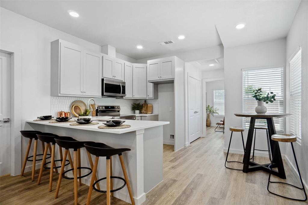 Kitchen with a peninsula, backsplash, visible vents, a kitchen bar, and appliances with stainless steel finishes