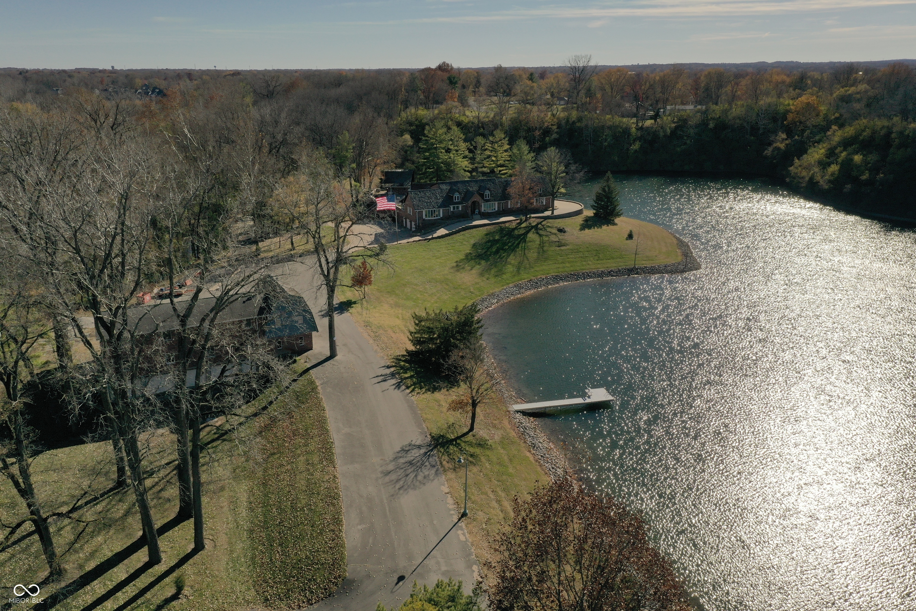 An extraordinary opportunity to own a true 1-owner, private estate featuring 2 homes on 19.638 breathtaking acres with lake frontage and unmatched 13 garage spaces. Tucked among mature trees and set along the waters edge, this property offers the perfect blend of luxury living, recreation and multi-generational flexibility. The grounds are remarkable-complete with an in-ground pool, pool house with covered patio, pickleball and basketball courts, swing beside a peaceful creek, and expansive open space providing both privacy and panoramic views. The main residence showcases a stunning 2-story entry welcoming you with an elegant front door and statement chandelier. The great room impresses with soaring ceiling, fireplace, stained glass accent window and windows framing serene lake views. The sunroom offers vaulted ceiling, skylights and sweeping views of the pool-creating a bright and inviting retreat. The kitchen is beautifully appointed with hardwood floors, built-in microwave and oven, abundant cabinetry, generous island space, solid-surface countertops and ideal layout for entertaining. The main-level primary suite is a private haven featuring lake views, spacious walk-in closet and luxurious en-suite bath with double vanities and walk-in shower. A second full bath and main-level laundry add functionality and comfort. Upstairs, a second primary suite with walk-in closet and private bath. 2 additional bedrooms-one with lake views-plus another full bath complete the upper level. Every bedroom includes ceiling fans for added comfort. Fully finished basement features 2 large bonus rooms, a half bath, newly installed vinyl plank flooring and direct access to the attached 2-car garage. The 2nd home offers a private apartment with 3 bedrooms, full bath, kitchen and living room-perfect for guests, extended family or income potential. This estate delivers luxury, space, recreation and privacy in one unparalleled offering.