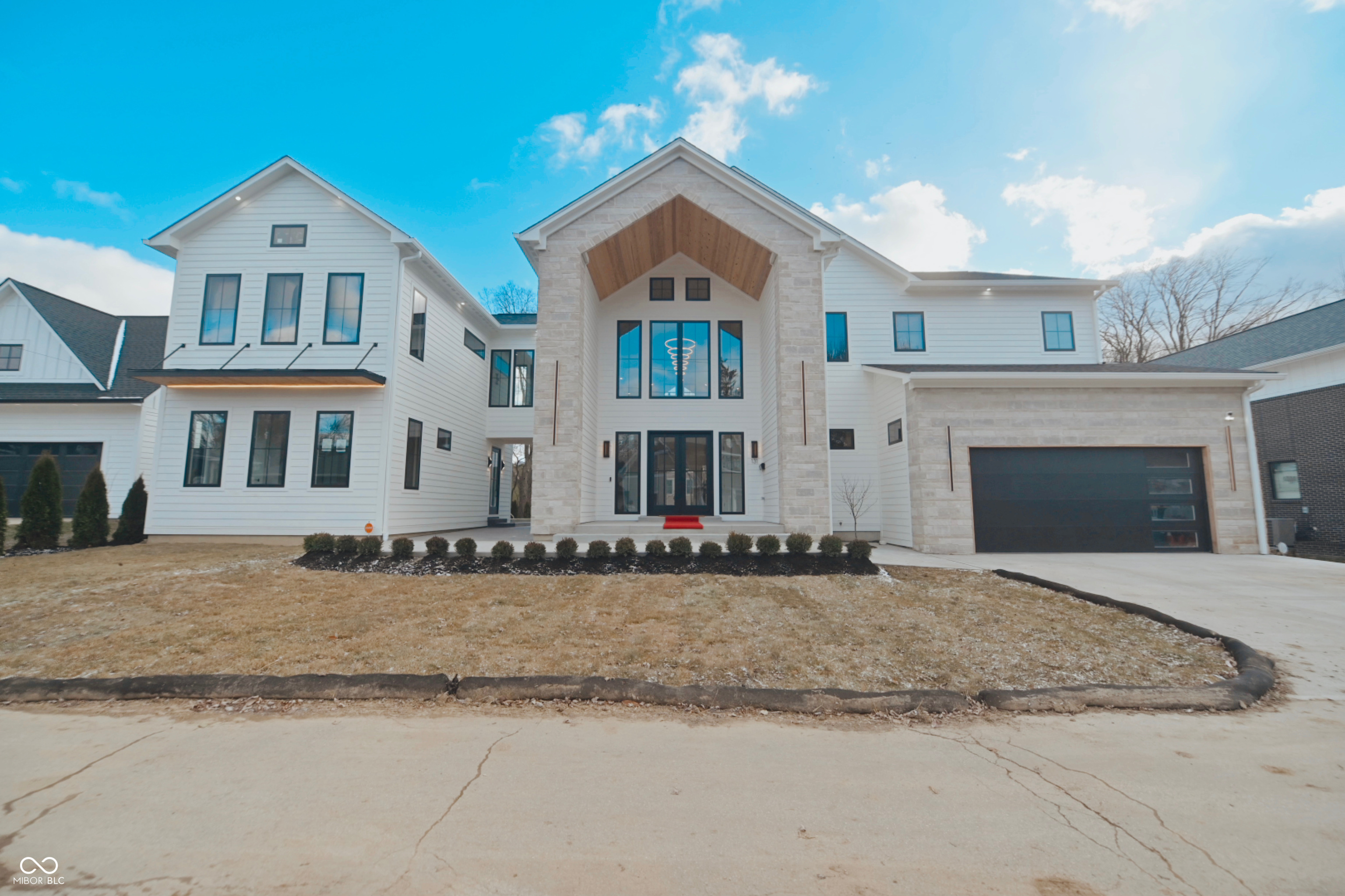 Welcome home to this stunning new construction residence located in the heart of the Arts and Design District in Carmel, Indiana. Just steps away from the Monon Trail, this exceptional home blends modern architecture with warm earth tones and organic finishes to create a truly one-of-a-kind living experience! Designed for everyday family comfort, but also equipped for elevated entertainment for guests. The home has clean lines, expansive windows throughout the home to capture surrounding views. The home has modern accents, and impeccable craftsmanship throughout.      The exterior welcomes you with a massive 20ft high covered porch with T&G wood ceilings, stone accents, and contemporary details. Once inside you will be wowed by the soaring 25ft high ceilings, modern chandeliers, and walls of windows flooding the home with tons of natural light. The home features 7" white oak hardwood floors, an open concept living area featuring a statement gas fireplace that has a seamless flow into the designer kitchen with custom cabinetry and a 30 bottle custom wine closet, premium appliances, an oversized island with walk in pantry.         You can effortlessly entertain guest with multiple indoor and outdoor gathering spaces including a private backyard retreat with in-ground heated pool and patio. A pool house with accordion doors open up to the outdoor space and offers a wet bar, bathroom and media space to escape the summer heat. The fully finished basement adds versatility with a large recreation space with a full media system including a 100-inch tv wall, plus a separate bar/game room behind custom arched glass doors.         Each of the 7 bathrooms are unique, with two bathrooms designed as private spa like retreats.  The master bathroom features travertine tile, heated floors, temperature-controlled faucets and a garden soaking tub.        Every detail of this residence reflects intentional design, quality materials, and a sophisticated modern aesthetic.