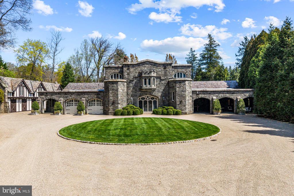 A stunning showcase of Tudor Revival architecture, 56 Crosby Brown Road is a set on 2.8 level acres on a private lane in the heart of Gladwyne on Philadelphia’s prestigious Main Line. Built between 1895–1905, this gorgeous, one-of-a-kind estate seamlessly blends historic grandeur with modern luxury. This exceptional property has been meticulously updated to provide every modern comfort with details executed to perfection.A dramatic entry Loggia leads you to grand leaded glass doors where you enter the foyer and center hall anchored by limestone with granite insets and custom limestone surrounds. Crowned by a soaring 25-foot beamed ceiling, the formal living room features a marble wood-burning fireplace with rich millwork and cabinetry, an impressive space for gatherings with access to one of three terraces that look out over the gardens. With its striking hand-crafted leaded glass window, the formal dining room is ideal for seamless entertaining, featuring a concealed doorway providing direct access to the butler’s pantry, wet bar and wine room. The main level also features an exquisite paneled library bathed in natural light from floor-to-ceiling sliders that lead you to the center terrace and gardens. Designed with exquisite custom artisan cabinetry by Downsview Kitchens and featuring Hereau fixtures, Miele appliances and Wolf ranges, this expansive kitchen flows effortlessly into the family room creating a warm and functional space for everyday living. Centered around a grand limestone gas fireplace, the family room offers a comfortable gathering place with direct access to the patio, outdoor kitchen and rear gardens. Adjacent to the kitchen, a spacious sun-drenched bonus room that formerly housed a lap pool with the potential to be restored, now serves as a bright gym and relaxed lounge area. Completing the main level is a laundry room, formal and informal powder rooms, and full bath.Ascend to the second floor, where dramatic 25-foot ceilings boast beams inlaid with hand painted canvases.The primary suite has vaulted ceilings, rich wood paneling with built-in closets, a sitting area, and an exquisite, extensively renovated ensuite bath featuring an Italian marble throughout and Sherele Wagner Fixtures. The second floor also features three sizable en-suite bedrooms, all benefiting from modern comforts and newly renovated bathrooms. One of these includes a welcoming gas fireplace.Next to the main home is a charming, completely renovated 2-bedroom, 1-bath carriage house with a full service kitchen. The half-timbered exterior recalls an English country home, while modern amenities provide today’s desired comforts. It can be used as a guest house or home office.A circular driveway with  attached garage; original stone potting shed, extensive stone terraces with outdoor kitchen; and meticulously landscaped yard and gardens that were once an arboretum complete this serene retreat.This historic gem is located in the prestigious Lower Merion School District just 1.7 miles from the Haverford and Ardmore train stations, with service to Phila. and NYC.  2 miles from Merion Cricket Club, 10 miles to center city Phila., close to various private schools, restaurants and shopping. With its unparalleled combination of history, craftsmanship, and modern elegance, 56 Crosby Brown Road is truly a Main Line legacy property.