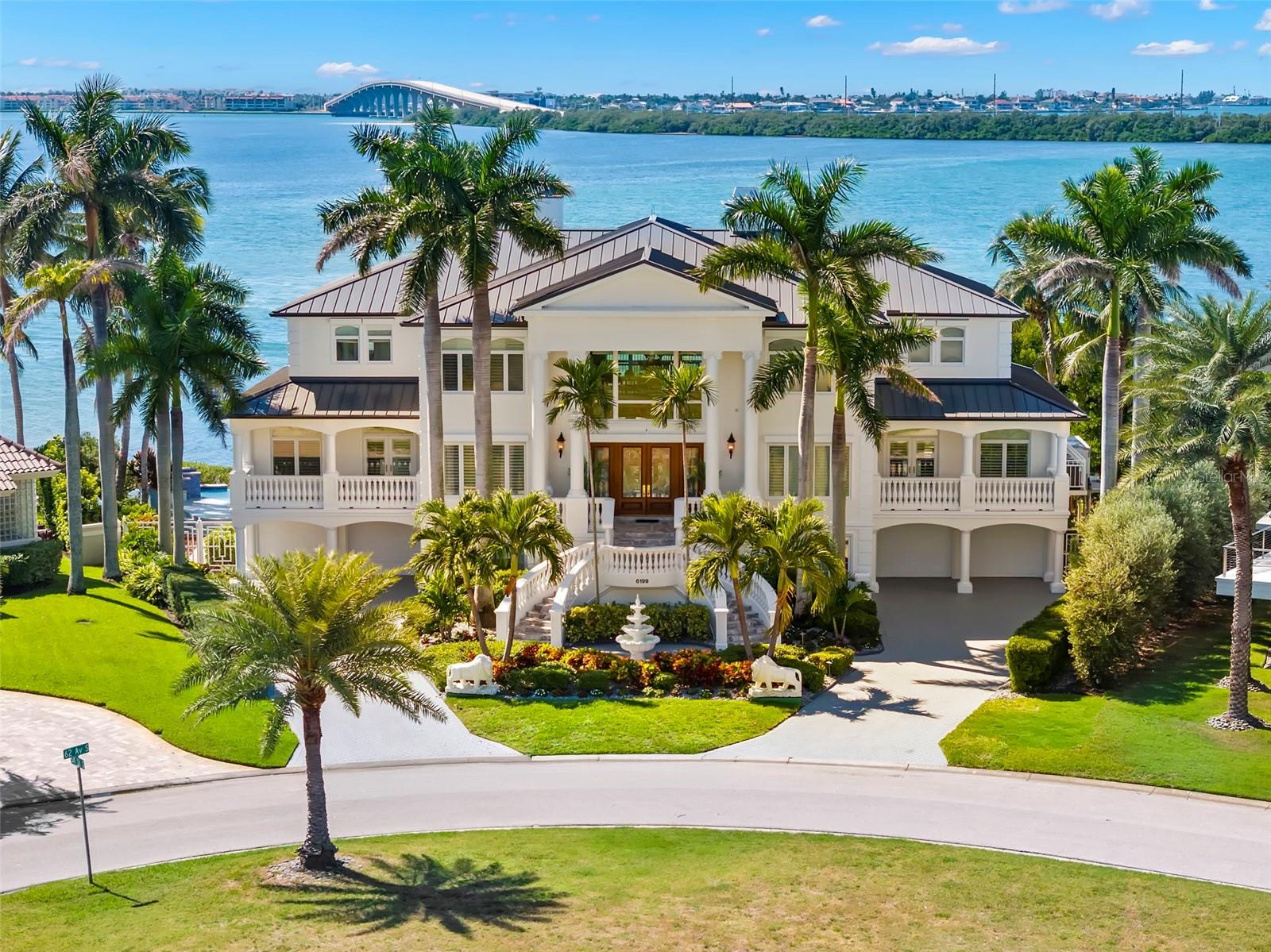 There are homes you live in and homes that elevate the way you live. This breathtaking waterfront estate does just that! Welcome to an extraordinary waterfront estate in the prestigious, guard-gated community of Bayway Isles. As you step through the stunning leaded glass double doors, your eyes are immediately drawn to the breathtaking open-water views. Perfectly positioned on an expansive point lot with 135 feet of waterfront, this residence captures spectacular sunsets and embodies the best of Florida luxury living. Spanning 7,114 square feet of living space with an impressive 3800 SF of fabulous balconies to enjoy outdoor living, this 5-bedroom, 5.5-bath home was designed with timeless elegance, impeccable craftsmanship, and effortless indoor-outdoor flow.  A private elevator servicing all levels immediately sets this residence apart, offering both convenience and luxury.  The home has recently undergone substantial upgrades, including a brand new charcoal-colored metal roof with lifetime warranty, freshly painted exterior, and a fully updated kitchen with modern white cabinetry and top-of-the-line stainless steel appliances.   The main living level features stunning marble flooring, a spacious great room with amazing water views, a custom wet bar, theater screen,a formal waterfront dining room and a convenient powder bath. Also on this level is a generous guest suite with en-suite bath, a walk-in pantry, and a fabulous office with built-ins. The top floor is dedicated to four bedroom suites arranged in a split plan, providing the generous primary suite its own private wing. The primary retreat showcases expansive water views, plantation shutters, a spacious custom walk-in closet with center island, and a newly remodeled bath with dual vanities, jacuzzi tub, walk-in shower, and abundant cabinetry. The refinished hardwood floors extend throughout the upper level, where all bedrooms are generously sized and filled with natural light.  Exceptional build quality of this all block constructed residence includes 6" poured concrete floors, hurricane shutters, a whole-house generator, and the split four-car garage features epoxy flooring. Also downstairs you have a private gym The resort-style backyard has been thoughtfully enhanced with a beautifully refurbished infinity-edge pool and deck, surrounded by lush tropical landscaping, and programmable lighting for year-round enjoyment. A brand-new dock with 16,000 lb boat lift, and new generator further elevate the home’s appeal. (Lastly there is a  low transferrable flood insurance (under $2,000 annually) and 1600 SF of additional bonus/storage area.  Ideally located just 10 minutes from vibrant Downtown St. Petersburg and 30 minutes to Tampa, with no bridges to open water, this exceptional estate offers a truly rare combination of luxury, lifestyle, and location.