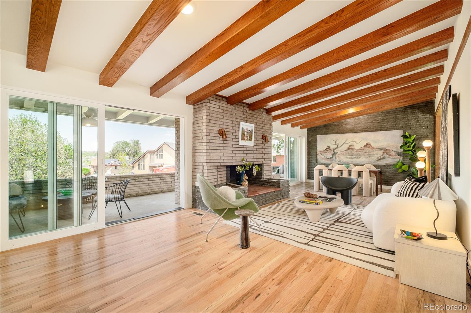 Meticulously reimagined from the foundation up, this mid-century modern residence sits steps from Sloan's Lake — one of Denver's most coveted waterfront settings. Every detail honors the home's architectural heritage while delivering the finishes today's most discerning buyers expect.A custom pivot door opens to soaring vaulted ceilings, exposed structural beams, and triple-pane sliding doors that frame an unobstructed panorama of Sloan's Lake. Stacked interior brick anchors the living spaces with texture and warmth, while massive sliding doors dissolve the boundary between indoors and out.The kitchen pays faithful homage to mid-century design — clean lines, intentional materials — while equipping you with everything a serious cook demands. A space that feels both of its era and entirely current.The primary suite is a study in restrained luxury: exposed beams overhead, lake views through huge picture windows, and an original wood-burning fireplace with a retro surround that grounds the room in character. The en-suite bath spans five zones — a 72-inch soaking tub, a private shower room, custom millwork, and handcrafted artisan tilework. This is not a bathroom; it is a retreat.The lower level continues the design language with another stacked-brick fireplace, a walkout to the yard, three generously scaled bedrooms, and two full baths — ideal for guests, a home office, or multi-generational living.Outside, a fully fenced lot faces the lake and is built for entertaining at every scale. The seamless indoor-outdoor flow makes the yard a natural extension of the living space. A detached two-car side-load garage adds rare convenience and storage for city living.Properties of this caliber — architecturally distinctive, obsessively renovated, and positioned on Sloan's Lake — do not come to market often. Schedule your private showing today.