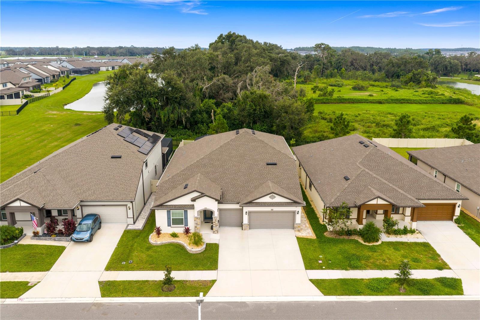 Welcome to your private retreat in the highly sought-after Epperson Lagoon Community, the first crystalline lagoon community in the United States. This impressive two-story residence offers 4,210 square feet of thoughtfully designed living space, blending modern elegance, comfort, and a lifestyle that feels like a permanent vacation.  Step inside to soaring ceilings, abundant natural light, and an open layout that flows effortlessly from room to room. The gourmet kitchen is a centerpiece with stainless steel appliances, quartz countertops, and a sleek central island overlooking the bright gathering room with expansive pool views. The first-floor owner’s suite is a spacious retreat with large windows framing the pool and a spa-inspired bathroom designed for relaxation. Two additional bedrooms, a versatile flex room, and two more full baths complete the downstairs living areas. Upstairs, you’ll discover two additional bedrooms, a full bath, a huge loft, and a media room that offer endless possibilities for entertainment, family living, or a dedicated work-from-home setup.  The home’s flooring enhances both style and functionality, with wood-look tile throughout the main floor living areas and plush carpeting in the loft, media room, and bedrooms for comfort.  The outdoor living space is built for enjoyment year-round. A heated pool and spa take center stage, complemented by a covered lanai and a complete outdoor kitchen that makes entertaining effortless. The fully fenced backyard provides privacy and space for both relaxation and recreation.  Additional features elevate the home’s convenience and value, blinds, designer lighting, a Rainbird irrigation system, and a three-car garage with overhead storage solutions. Wired speakers throughout the home make it easy to enjoy music in every living space.  Epperson Ranch offers a truly unique lifestyle with its seven-acre crystal lagoon, unlimited household access, and annual guest passes. The community also includes Eagle’s Nest Park, Elam Park, a dog park, golf cart paths, and family-friendly events. High-speed internet and cable are included in the HOA, making daily living seamless and connected.  The location offers the best of Wesley Chapel living, with top-rated schools, shopping at The Shops at Wiregrass and Tampa Premium Outlets, an array of dining options, and convenient access to major highways for easy commutes across the Tampa Bay area.  This home is more than just a place to live—it is an opportunity to enjoy resort-style amenities and everyday comfort in one of Florida’s most desirable communities. Schedule your private showing today and see why Epperson Lagoon living is truly one-of-a-kind.