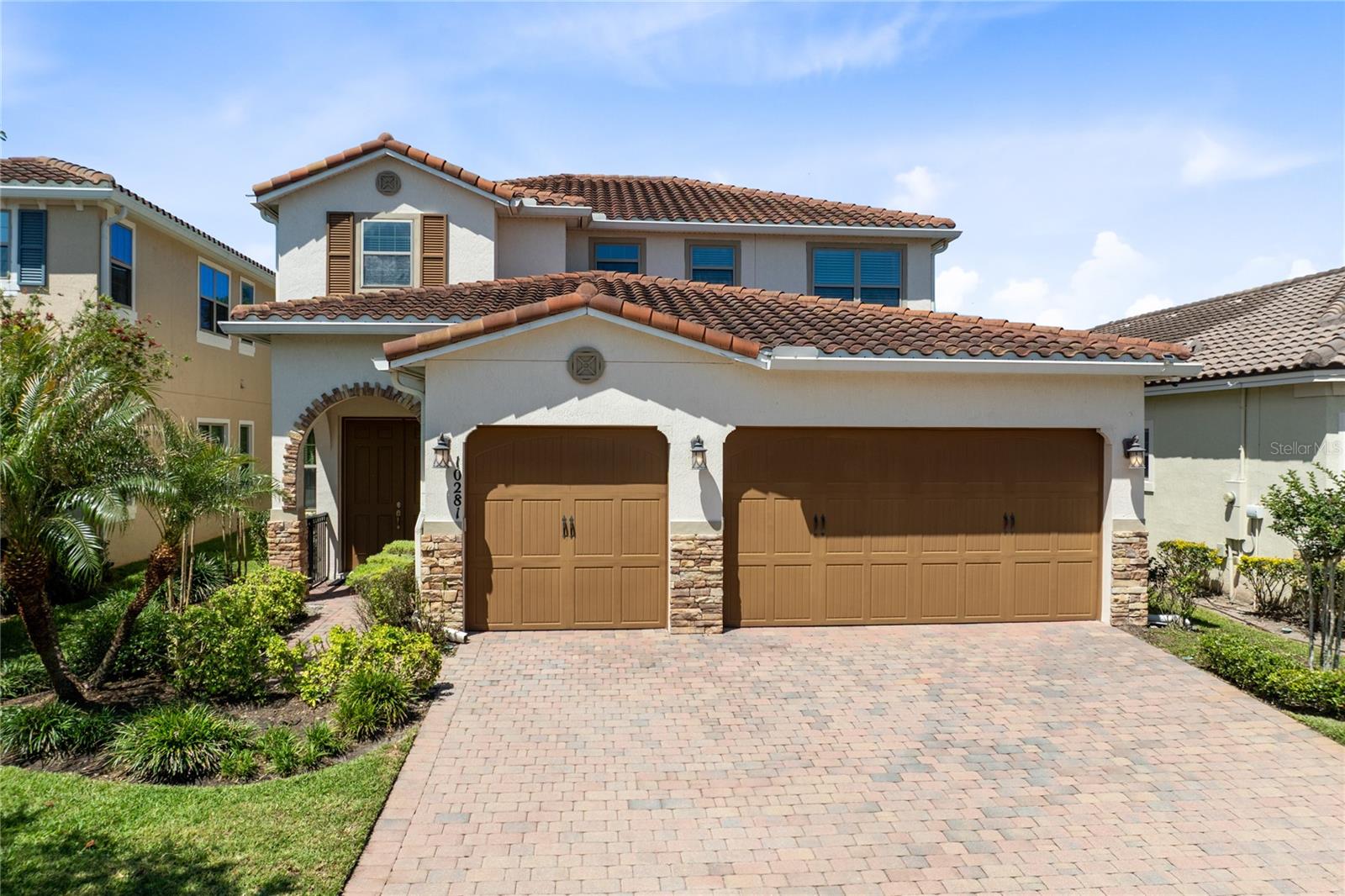 Built in 2018 inside the gates of Eagle Creek, this 4-bedroom, 3.5-bath Spanish Mediterranean home spans 2,873 square feet across two floors and a 3-car garage. The main level holds the primary suite and three separate living spaces. The second floor holds three bedrooms, a dedicated office, and a bonus room.Wood-look plank tile runs the length of the main floor without a break. A formal great room and dining space sit at the front under an iron-balustered staircase. The kitchen takes the middle: granite island, dark espresso cabinetry stacked to the ceiling, glass-mosaic backsplash, stainless appliances under a chimney hood, and a bay-window breakfast nook for morning coffee. The family room sits at the back, with sliders to the covered patio and a clear sightline from the kitchen island all the way to the yard.The primary suite is the floor plan's signature. The bedroom runs nearly 27 feet under a tray ceiling and opens directly to the covered patio through its own slider. The bathroom is laid out for two: dual vanities flanking a makeup station, glass rain shower, corner garden tub set under a window, and a private water closet. Two walk-in closets share the wall with the bath.Upstairs answers the rest of the program. A dedicated office at the top of the stairs. Three bedrooms, two of them sharing a Jack and Jill bath. And a bonus room over 21 feet long, already wired with in-ceiling speakers and currently set up for movie nights.Outside, a covered patio runs the full back wall under a deep overhang built for Florida afternoons. Two sliders reach it, one from the family room and one from the primary, so the social and private sides of the house each get their own way out. The fenced yard backs to a tree-buffered green corridor instead of another rooftop, which is rarer in this part of Eagle Creek than the lot description suggests.Behind the gates: clubhouse, resort-style pool, tennis, fitness, and a championship golf course. Beyond them: Lake Nona Town Center, Medical City, and OIA, all a short drive away. And inside this particular front door: the one floor plan in the neighborhood that lets you stay on the main floor for everything you actually need, and head upstairs only when you want to.