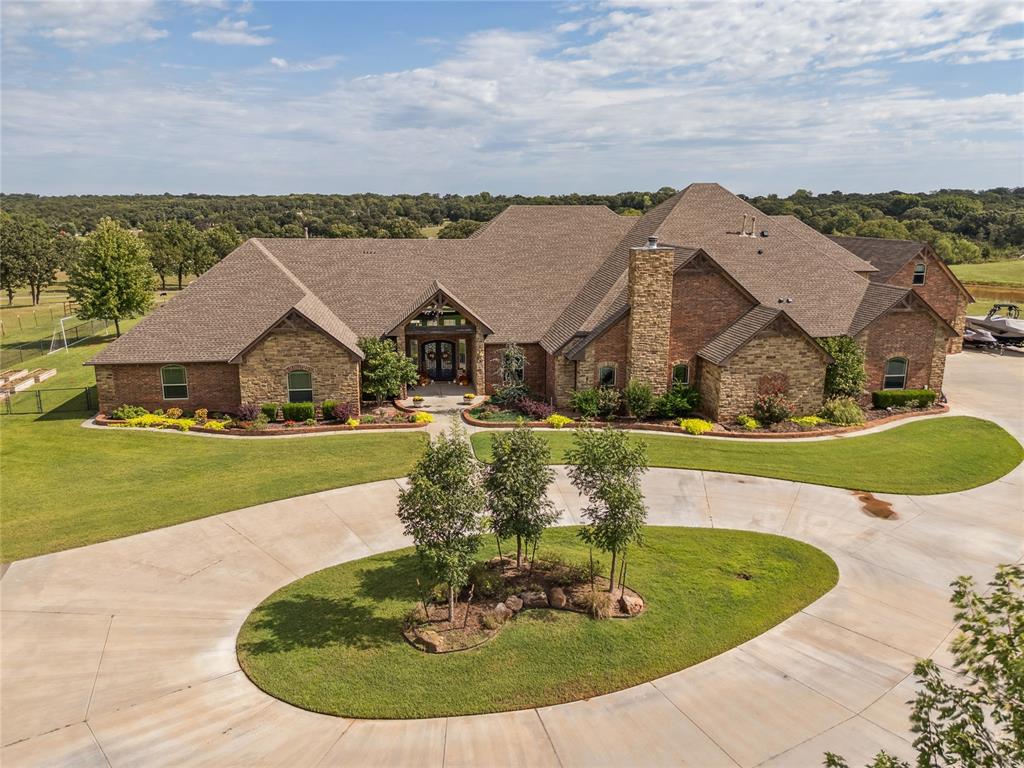 Experience refined luxury and self-sufficient living on this 142.3-acre private estate—crafted with exceptional detail and design. The primary suite impresses with a vaulted beam ceiling, hand-scraped walnut floors, and a wood-burning fireplace with a cozy sitting area. Its spa-style en-suite features a walk-in shower with dual heads, a large soaking tub, and an oversized walk-in closet that doubles as an F5-rated safe room. Each secondary bedroom includes its own private bath and walk-in closet. The executive office offers hand-scraped wood floors and built-in shelving, while the gourmet kitchen is a chef’s dream—complete with two islands, farmhouse and prep sinks, two dishwashers, reverse osmosis water filtration system, South-Bend 10-burner gas stove with double ovens and broiler, custom vent hood, Sub-Zero refrigerator/freezer, and walk-in pantry with custom wood accent above the kitchen. The laundry room includes dual washers and dryers, a rolling island, wash sink, built-in storage, mudroom, and secondary office space. Upstairs features a game room, media room, and exercise room, while a climate-controlled dog room with auto door and wash area enhances everyday convenience. Luxury continues with vaulted beam entry and formal living room, motorized shades, plantation shutters, smart thermostat, spray foam insulation, private sauna and security system with 8-zone cameras. Outdoors, enjoy a 35,000-gallon heated saltwater pool with tanning ledge, diving board, slide, and 10-person hot tub. A 20x40 sports court features three basketball goals, pickleball/volleyball lines, and LED lighting. The 8-stall horse barn includes a tack room, wash rack, and roll-up doors, surrounded by six pastures and three paddocks with water access. Property also includes four water wells, large pond, Rain Bird sprinkler system, and two rental homes—perfect for guests or income opportunities. Every detail of this estate blends comfort, elegance, and functionality in perfect harmony.