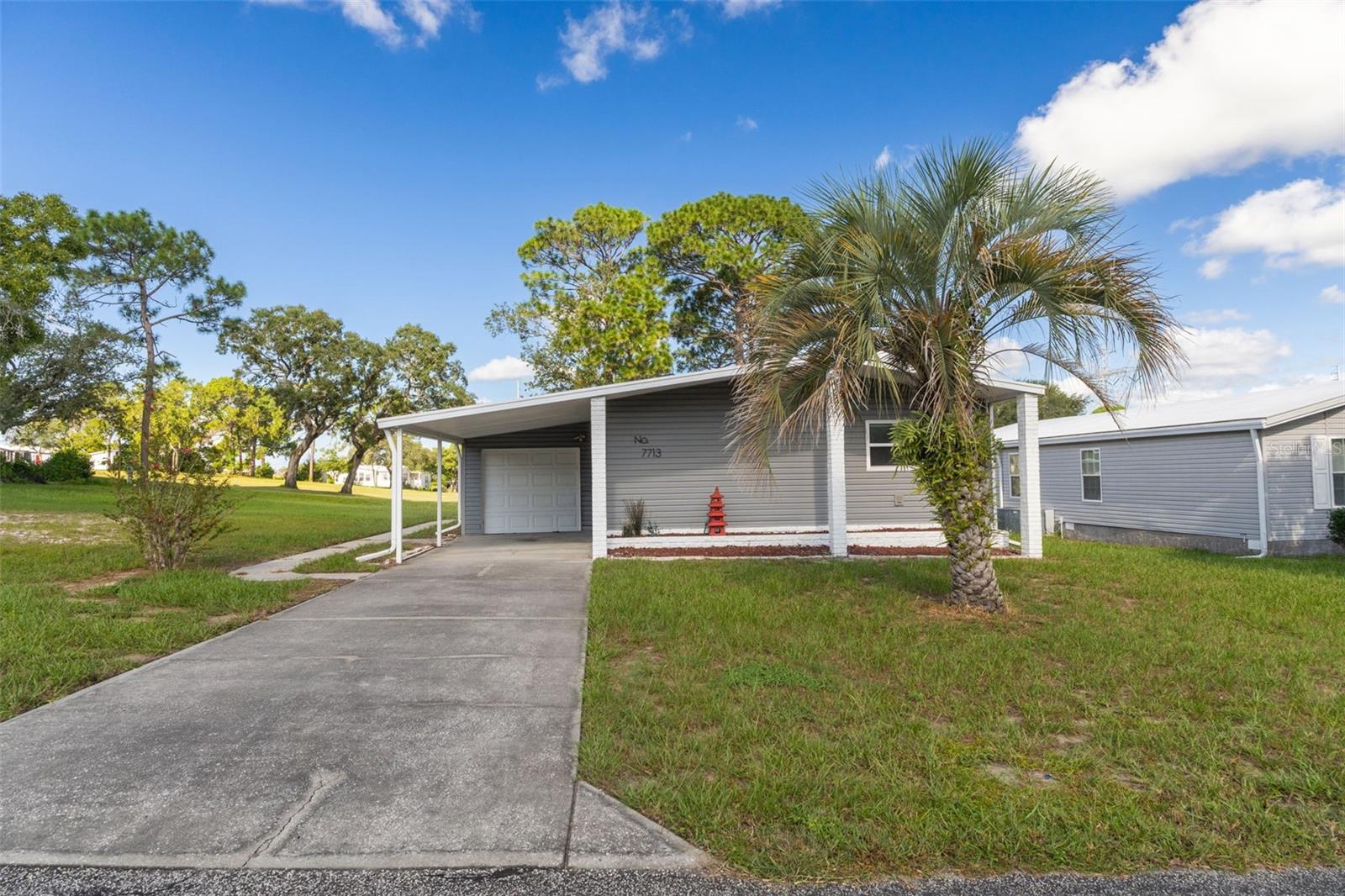 Virtually Staged. RARE GOLF COURSE OPPORTUNITY PRICED TO MOVE IMMEDIATELY!Imagine waking up each morning to serene green vistas and stepping right onto the golf course. Located in the heart of Brooksville, 7713 Moriah Ave offers more than just a home—it provides an active, engaging lifestyle in a vibrant golf course community where neighbors truly feel like friends and community events are always on the calendar. Best of all, you OWN THE LAND outright with no land-lease worries.From the moment you arrive, the home greets you with extensive major updates completed in 2020, including DURABLE VINYL SIDING, ENERGY-EFFICIENT DOUBLE PANED WINDOWS, a modern TPO ROOF, and an updated AC system to keep you cool year-round. Inside, an airy OPEN FLOOR PLAN creates a seamless flow for daily living and entertaining.The heart of the home extends into a bright, ENCLOSED SUNROOM—the ideal spot for morning coffee while watching golfers tee off—which opens to a SPACIOUS DECK added in 2018, perfect for weekend barbecues and evening relaxation.Every detail has been thoughtfully designed for convenience and comfort.  The kitchen is outfitted with NEWER APPLIANCES and a PANTRY.  The CENTER ISLAND offers a natural gathering spot where family and friends can chat with the chef without crowding the workspace.  The primary suite features a WALK IN SHOWER designed for ease of use, paired with a custom CEDAR-LINED WALK IN CLOSET.  A convenient GOLF CART GARAGE offers secure parking and space for extra storage.  Adjacent is the designated LAUNDRY ROOM for ease of use.This property is priced aggressively for a FAST sale!!  With a highly motivated seller, this turnkey golf course retreat is priced to move. Schedule your private showing today and start living the land-owned golf community dream!