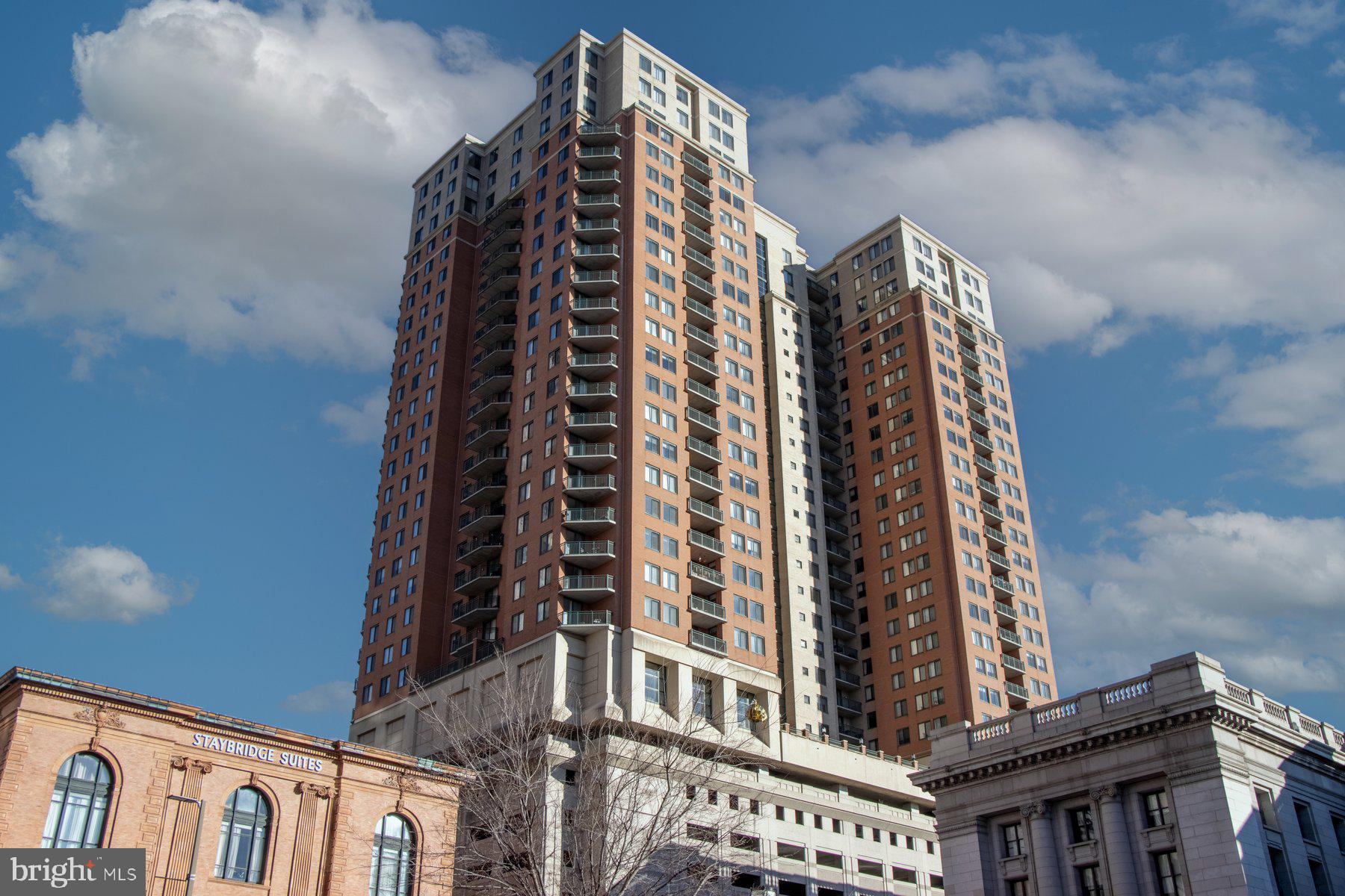 Luxury Condo living awaits you featuring a 2BR/2BA high rise unit with stunning views of the Baltimore skyline. Step into a beautifully maintained secure building, take the elevator to the 25th floor, and make your way to the door into your new home.  The open concept floor plan offers a large living room with a gas burning fireplace, a spacious dining area, and a kitchen. The kitchen features plenty of cabinets including a separate pantry cabinet, granite countertops with a complimenting tiled backsplash, and a stainless sink under a raised breakfast bar.  Down the hall is a spacious secondary bedroom, a full bath with a deep soaking tub, laundry, and a large primary bedroom featuring a walk-in closet with custom organizers, a second closet, and a private bath with a walk-in shower. Just off the kitchen is a cozy balcony offering stunning views of the surrounding city skyline.  This home is move-in ready featuring recessed lighting and gleaming hardwood floors, and is located in a building offering not one but two pools, a community room with a kitchen and bar, a gym, and so much more.  Imagine all this and in close proximity to shopping, restaurants, and commuter routes. Rare find with two parking spots and additional storage!