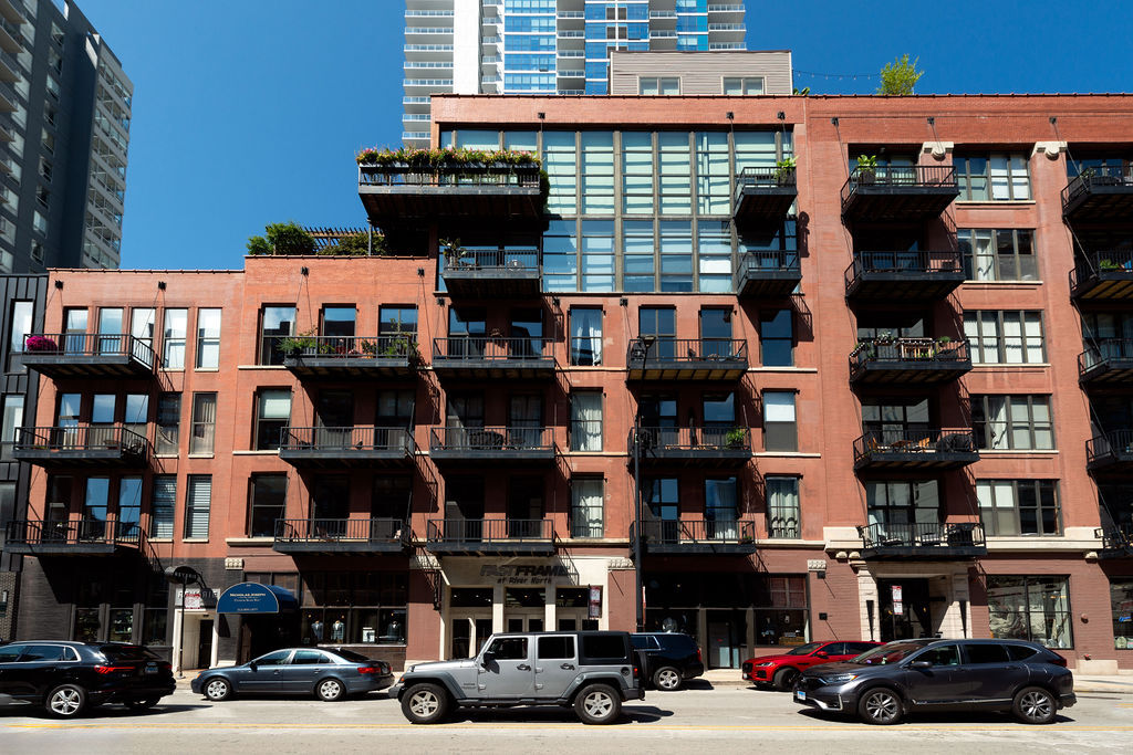 Enjoy this beautiful brick and timber 2 bed /2 bath loft unit in River North. With super sunny south-facing exposure, this end unit fills with light from floor to ceiling windows and features soaring thick-beamed ceilings and exposed brick in every room with two fully enclosed bedrooms. Remodeled in 2021, the kitchen features 42" Edgecomb Gray cabinets, all stainless steel Kitchen-Aid appliances, Artic White quartz counters, translucent glass backsplash, extra deep under-mount sink, faucet with sprayer, and under-cabinet lighting, plus a beautiful new bar area with beverage storage. Hardwood floors have been added new in the bedroom and have been refinished throughout in a natural matte oak finish while the living/dining rooms are open and ideal for entertaining with a new composite decking balcony off the living room. A gas start fireplace is included and perfect for cozy-ups in winter. This split floor plan is ideal for a work-from-home office while still allowing for a complete guest suite. The primary bedroom is large enough for a king-sized bed and the entire unit has been freshly painted with tons of organized closets. A new Bryant 2.5 ton air conditioner was installed in July 2020 plus  brand new Lenox furnace in 2025 including a convenient remote control Nest thermostat. Deeded garage parking is available for $25K. A walk-in storage room is also included. Building also has a brand new common roof deck. Location is ideal convenient to plenty of restaurants, bars, transportation and East Bank Club. A loft lovers dream in River North.