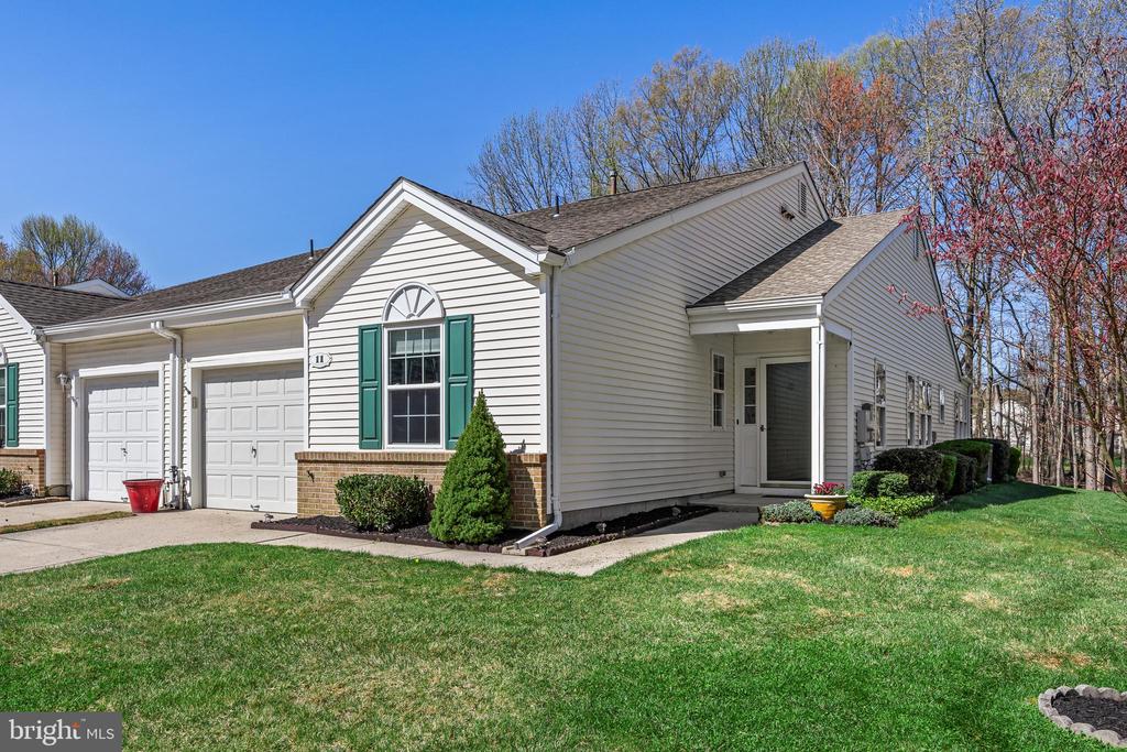 Tucked away on a quiet cul-de-sac and backing to serene woods, this beautifully maintained 2-bedroom, 2-bath patio home offers the perfect blend of comfort, privacy, and easy living in a vibrant 55+ community.Step inside to an inviting open-concept great room, where crown molding, a charming faux fireplace, and defined dining and living spaces create a warm and welcoming atmosphere—ideal for both relaxing and entertaining. Just off the main living area, the second bedroom and full bath are thoughtfully positioned, offering comfort and privacy for guests.The spacious primary suite is a true retreat, featuring a separate ensuite with a dressing area complete with two large closets with built-in organizers and a dedicated sink. A separate shower and private toilet room enhance both functionality and comfort.The bright, updated kitchen is a standout feature, boasting white cabinetry, granite countertops, an undermount sink, and a large island with seating for four—complete with pull-out trash and recycling. Thoughtful storage solutions abound, including upper corner cabinetry with three Lazy Susan shelves, a lower corner cabinet with stationary shelving, and a pantry with pull-out shelves. A built-in desk area with additional cabinetry provides the perfect space for organization or work-from-home needs.Flowing seamlessly from the kitchen is a sun-drenched Florida room filled with windows and a sliding glass door leading to a concrete patio. Two electric awnings provide shade on sunny days, creating an ideal outdoor retreat. Enjoy peaceful backyard views of the woods and local wildlife—your own private escape.Residents of this sought-after 55+ community enjoy access to a clubhouse with an array of amenities, including an outdoor pool, tennis courts, pickleball, an exercise room, and a full calendar of social activities and programs.This home offers the perfect combination of low-maintenance living, thoughtful updates, and a tranquil natural setting—ready for you to move in and enjoy.