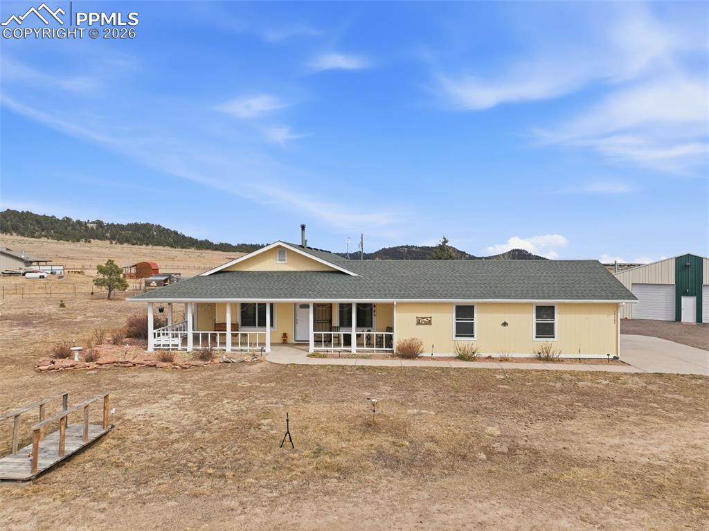 This custom rancher sits on 5 acres with a 40x40 detached shop, a barn, chicken coop, green house, and breathtaking views of Pikes Peak! This thoughtfully designed home features an expansive great room with vaulted ceilings, live-edge entertainment wall, and wood-burning stove. The spacious kitchen offers knotty oak cabinetry, large island with breakfast bar, walk-in pantry, and built-in serving hutch. The primary suite includes a five-piece bath with jetted tub and private patio access. Radiant heat throughout, a sunroom, dedicated office, mudroom with dog wash, and wraparound covered porch perfectly positioned for Pikes Peak views. a 2 car attached garage plus the insulated shop features a heated office/workshop area, garage doors for RV or boat storage, and 220V power. Fully fenced horse property with a new barn, loafing shed, & seasonal pond. This is a home you don't want to miss!