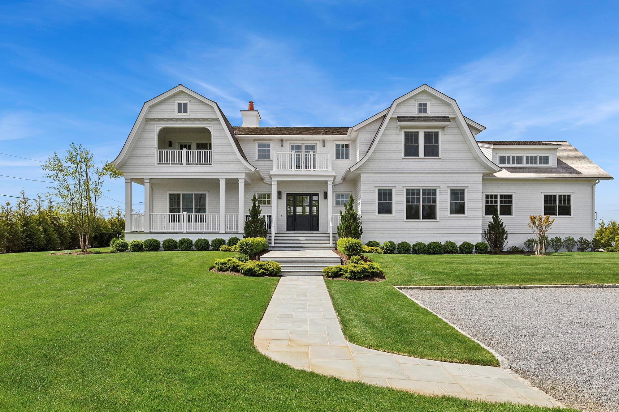 The epitome of Hamptons luxury awaits at this newly constructed 2023 estate designed with uncompromising craftsmanship and an eye for elevated coastal living. Set on 1.13 pristine acres south of the highway, this 5-bedroom, 5.5-bathroom masterpiece spans 5,550 square feet and offers sweeping views of Moriches Bay, just minutes from the charm and convenience of Westhampton Beach's Main Street. From the moment you enter the grand foyer, the home exudes thoughtful sophistication-showcasing 7" white oak flooring, solid core doors, custom closets, and Hunter Douglas window treatments throughout, including automated shades in the upstairs primary suite. The open-concept layout is anchored by a dramatic double-height living room with soaring 20-foot ceilings, a striking 42" gas fireplace, and stunning water views, all flowing seamlessly into the expansive backyard retreat. At the heart of the home is a show-stopping chef's kitchen, outfitted with top-of-the-line Sub-Zero and Wolf appliances, Caesarstone countertops, an oversized center island with seating for four, double dishwashers, warming drawer, and custom cabinetry. A walk-in pantry adds convenience and flair, equipped with a Wolf microwave drawer, XO wine refrigerator, and abundant storage. Also on the main level, a custom-built office offers a private workspace, while the first-floor junior primary suite enjoys tranquil views of the backyard, pool, and bay. Its spa-like bath features a 72" Pottery Barn double vanity, radiant heat floors, soaking tub, walk-in shower with rainfall shower head, and a custom-designed walk-in closet. A separate guest suite provides privacy down a quiet corridor. The mudroom with herringbone tile, custom cabinetry, full laundry, and pool bath completes the main floor. Upstairs, the second level stuns with views of Moriches Bay from nearly all rooms & offers three additional ensuite bedrooms, including the primary retreat. The primary suite opens to a private waterside balcony overlooking the lush grounds and includes oversized walk-in closet, a linen closet, and a luxurious bath adorned with Carrara marble, radiant heat floors, soaking tub, rainfall shower, and a second secluded balcony. A large bonus room with bay views and an additional laundry room add to the second level's thoughtful design. The outdoor living experience is nothing short of exceptional. A bluestone patio extends from the great room and mudroom to a 20' x 20' covered lounge complete with a fireplace and wall-mounted TV-ideal for entertaining. The fully equipped outdoor kitchen features a built-in Mont Alpi 6-burner BBQ with additional side burner, sink, beverage refrigerator, and storage. The 20' x 40' saltwater, heated, gunite pool with spa and bluestone surround invites ultimate relaxation, while mature arborvitaes provide exceptional privacy along the property perimeter. Additional features include a two-car garage with epoxy floors, IA septic system, Nest-controlled 5-zone HVAC, whole-home air purification, and a full Honeywell security system with Ring integration. Located in the sought-after estate section of Westhampton Beach, just 2.7 miles to Rogers Beach, this impeccable property offers the ultimate Hamptons lifestyle-modern, private, and just 78 miles from Manhattan.