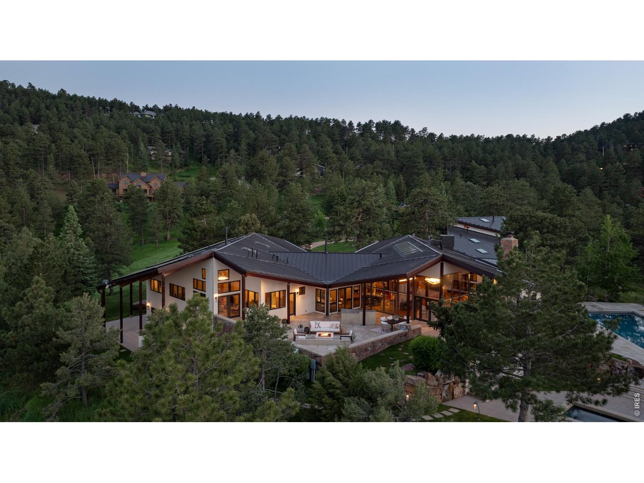 A private 10.6-acre mountain sanctuary less than 10 minutes from Downtown Boulder and Pearl Street. Set on one of Pine Brook Hills' most extraordinary parcels, 1530 Timber Lane combines expansive, gently sloping land, 360-degree views, resort-style amenities and architectural pedigree in a setting that feels worlds away from the city.Designed by renowned Boulder architect Hobart D. Wagener with Jay Nold Midyette, the 7,016-square-foot residence was created around natural light, views and a seamless connection to the outdoors. Walls of glass and 25 skylights illuminate warm, richly detailed interiors with Brazilian cherry hardwood, stone, Venetian plaster and cedar-clad vaulted ceilings. The expansive kitchen features Wolf and Sub-Zero appliances, soapstone countertops, a walk-in pantry and adjoining fireside lounge. A dramatic great room, sunken fireplace sitting area, library, art studio, home theater and office provide spaces for both everyday living and entertaining. The main-level primary suite is a private retreat with walls of windows, a fireside sitting room, spa bath and direct outdoor access. Separate guest quarters above the heated three-car garage offer additional privacy and flexibility. Outside, the property unfolds like a private resort: saltwater pool, 10-person spa, 8-person sauna, multiple patios and gazebos, a 6,000-square-foot park lawn and private hiking and mountain biking trails. Extensive landscaping, mature trees and exceptional infrastructure complete this rare Boulder estate.Mountain privacy. Remarkable land. Minutes from everything that makes Boulder extraordinary.