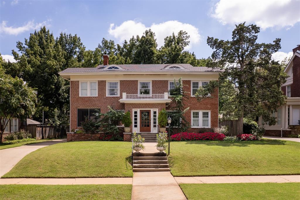 1925 Georgian Colonial Revival in Gatewood. Preserved details, timeless style, mature grounds and a location on one of the neighborhood’s most distinguished streets make it truly special. Its symmetrical red-brick façade, classical proportions and sweeping lawn are framed by mature trees and lush, layered landscaping that create a memorable approach. Natural light streams through divided light windows in the living room, a period detail of the style. A gas fireplace with a classic mantel adds warmth and creates a natural gathering place, while the adjoining library, enclosed by French doors, provides a quiet retreat. Hardwood floors run throughout the home, complemented by antique lighting that adds character and history to every room. The dining room offers a welcoming setting for gatherings, while the kitchen blends heritage with modern function, featuring marble counters, a farmhouse sink, subway tile, brass hardware and an exposed brick chimney. Saddle stairs connect the spaces with both function and charm. Upstairs, the primary suite includes a private bath, period mantel and generous closet. Three additional bedrooms offer flexibility for an additional living if desired. The hall bath showcases William Morris wallpaper and fixtures that honor the home’s historic character. Upstairs laundry adds everyday ease. The screened-in side porch is a retreat of its own, extending living space into the landscape. The 0.26-acre yard includes an automatic gate and outdoor areas for dining, gardening and unwinding. A fully renovated garage apartment offers complete living quarters with Murphy bed, bath and kitchenette—ideal for guests, office or income. Other features include generous drop zone closet, basement for storage, a replaced sewer line, drainage system, whole-home air filtration system, window updates and more. In OKC’s beloved Gatewood District, this home pairs architectural significance with everyday livability. History and style, ready for you to call it home.