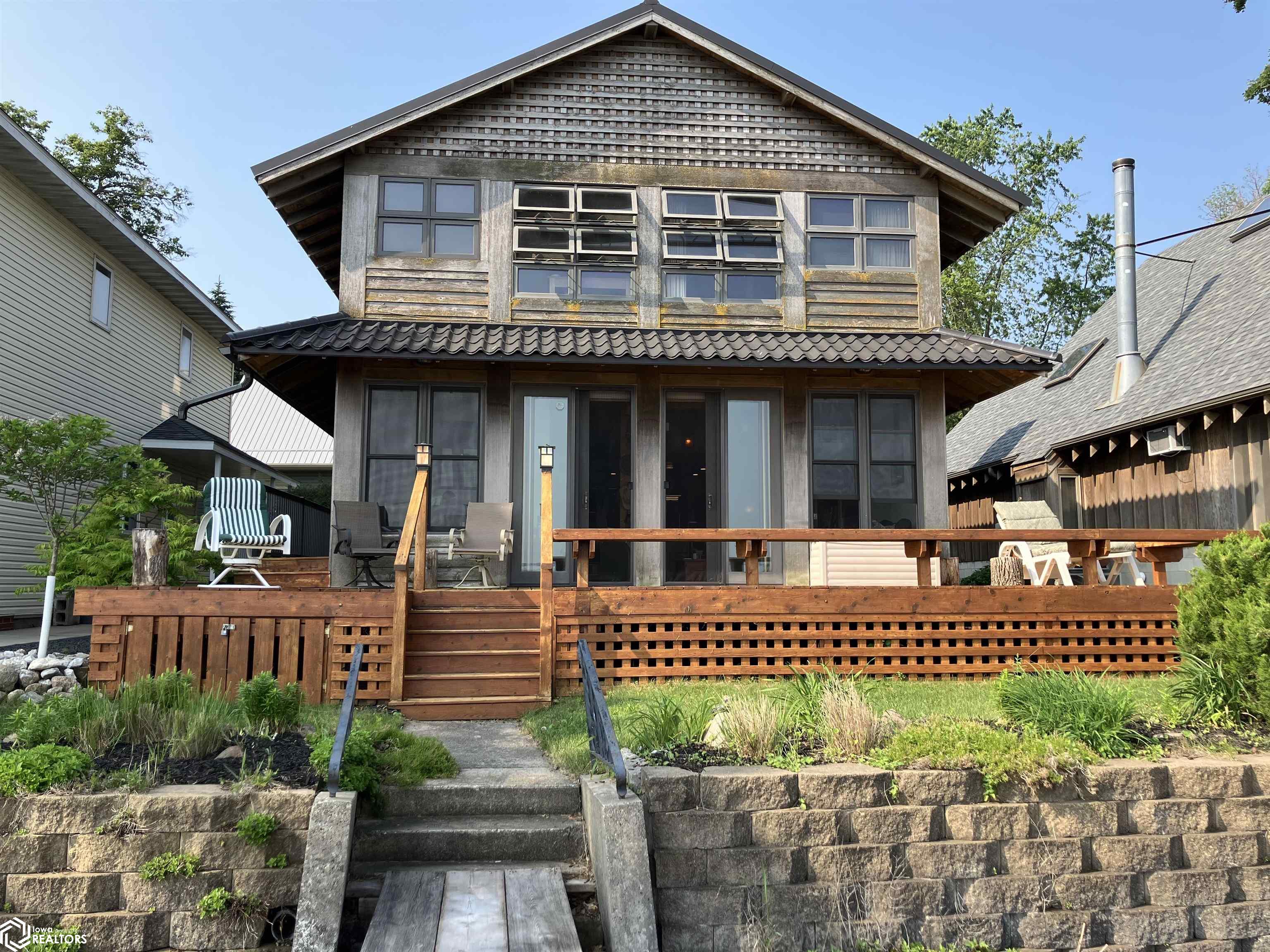 Stylish South Shore year round home on 40 ft. of landscaped lakefront. Property family owned since 1928.  Architect designed and newly rebuilt by Meints Construction in 2000.  Home to be sold turnkey with unique, tasteful furnishings.  Open plan, cathedral ceiling, with second floor sleeping quarters rear and lakeside.  Additional smaller room upstairs with lake view.  Full baths up and down are Italian tiled and teakwood finished.  Beautiful hardwood floor throughout open downstairs kitchen, living area steps down to tiled sitting, entertaining area plus large desk alcove.  Walk out through ceiling to floor  double sliders to full 30 x 15 ft deck and wrap around walkway, and further down to 70 ft. dock, included. Wood burning fireplace on raised hearth between underlit, built in bookcases. Wired for sound throughout. Furnace, water heater replaced in 2020; central air new in 2024. Parking for 3 cars and much more - truly must see to appreciate.