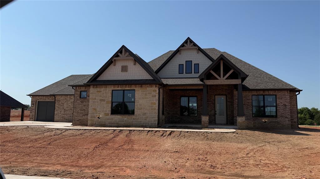 This modern rustic house features four bedrooms and three and a half bathrooms, combining contemporary design elements with natural, rustic accents. The house boasts a charming exterior with modern and rustic elements. The facade combines clean lines, natural materials, stone, and wood, creating a warm and inviting atmosphere. Large windows and a covered porch provide an excellent connection to the outdoors. Upon entering, you step into an open-concept living area that seamlessly integrates the kitchen, dining room, and living room. The space is characterized by high ceilings, a stone fireplace, and large windows, allowing ample natural light to flood the area. The flooring is light creating a modern rustic feel. The kitchen features sleek, modern appliances and fixtures. Cabinets with a dark finish add a touch of rustic elegance, while a large center island provides additional workspace and doubles as a breakfast bar. Nestled off of the kitchen are 3 secondary bedrooms and two baths that are anchored by a second living area. This is a great space to watch a movie, do homework or play games. The primary retreat features rustic beams with a lot of natural light. You will love the seclusion this retreat offers as well as the spa-like bath. The center stage of the primary bath is the freestanding tub. Relaxation is easy in this space. The Primary Closet has a center chest of drawers with 3rd-row seasoning rods. If you love outdoor living this home has it. There is plenty of space for a seating and dining area around the outdoor fireplace. A study, 1/2 bath, & formal dining complete this home. Owner is licensee. O/A
