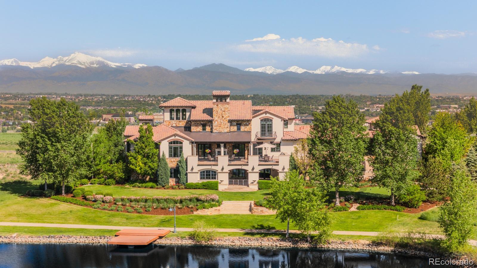 On a private lakefront acre at the highest vantage point in Broomfield’s most prestigious gated enclave, 1820 Mallard Drive is a residence of rare distinction where architectural brilliance, natural grandeur and refined comfort converge in flawless harmony. With panoramic views of the Rocky Mountains and a shimmering private lake as its ever-changing backdrop, this 11,000 square foot estate is a triumph of design and lifestyle, curated for the discerning few. A tree-canopied approach winds past still waters arriving at a circular drive, sweeping archways and grand portico that rises like a timeless sculpture from the verdant landscape. Every artisan detail from the grand gallery hall and soaring timber-beamed ceilings to the hand-chiseled stone and luminous lighting has been conceived to evoke awe and inspiration. The reimagined William Ohs kitchen is a culinary celebration of form and function, wrapped in Taj Mahal quartzite and bespoke walnut cabinetry, anchored by a chef’s suite of Sub-Zero and Wolf appliances. Impressing with 22-foot ceilings and a monumental stone fireplace, the great room invites both intimate gatherings and grand entertaining. Walls of glass slide away to reveal heated terraces with fireplaces and unforgettable views. The main level primary suite is a private haven of indulgence, with a lake-facing soaking tub, dual water closets, steam shower, morning bar and couture-worthy dressing rooms. Upstairs, two luxe suites enjoy their own vistas, while the third-floor Sky Loft offers a 270° panorama perfect for creativity and reflection. The walk-out lower level is a destination in itself with billiards and media lounges, a stunning bar, spa room, private gym, and guest quarters. Beyond, layered patios and terraces, a putting green and private dock invite outdoor living in all seasons. With seven garage bays, Savant smart home integration and a setting that bridges Boulder and Denver, this is not merely a residence, it’s a legacy of artful living.