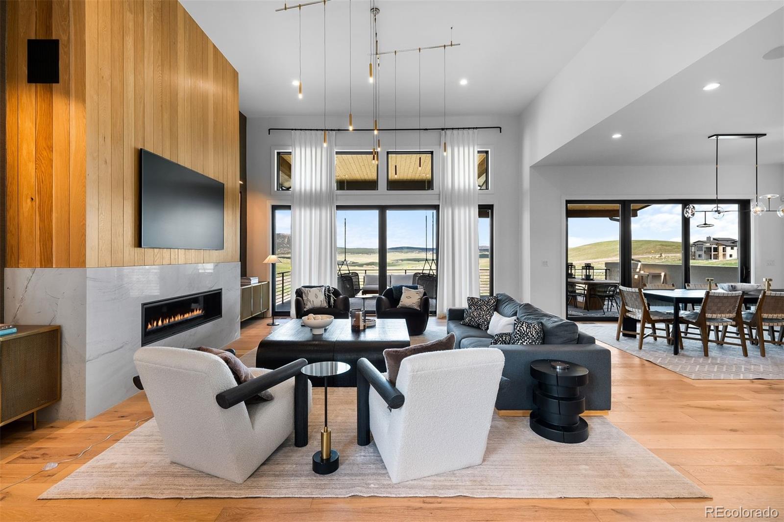 Framed by open space and Dawson Butte views, this custom contemporary masterpiece blends striking architecture with warm, livable design. Wide-plank white oak floors, soaring ceilings, clean lines, and walls of glass create a home that feels as impressive as it is inviting.A floating open-riser staircase makes a stunning first impression, leading into a dramatic great room with 13-foot ceilings, a marble-wrapped fireplace framed by white oak tongue-and-groove, and seamless indoor-outdoor living. The gourmet kitchen is equally impressive, featuring floor-to-ceiling white oak cabinetry, a quartz waterfall island, premium Monogram appliances, and an oversized dining area. Two sliding doors open to a full-length covered deck overlooking open space & Colorado sunsets.The primary suite is a true retreat with vaulted tongue-and-groove ceilings, fireplace, window seat, dual custom walk-in closets, and a spa-inspired bath with freestanding tub, frameless multi-head shower, and dual floating marble vanities.Designed for entertaining, the walkout lower level offers a spacious recreation room with matching marble-and-oak fireplace, sleek wet bar, private exercise room, guest accommodations, abundant storage, and a playful kids' retreat complete with a built-in fort. Sliding doors extend the living space to a covered patio and professionally landscaped yard.Completed in 2023 with nearly 6,000 finished sq ft, this move-in-ready home offers exceptional design, thoughtful functionality, and convenient access to Castle Rock, Denver, Colorado Springs, hiking, golf, and endless outdoor recreation.Bold architecture. Designer finishes. An exceptional value.
