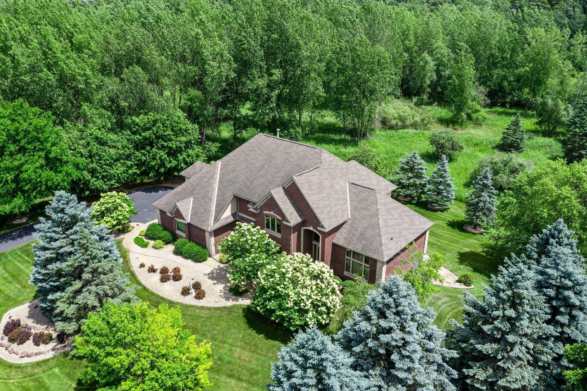 This meticulously maintained, stunning custom-built 5-bedroom, 4-bathroom home is nestled on a peaceful cul-de-sac in Dellwood, offering modern convenience and tranquil, nature-filled surroundings. The kitchen is a chef's dream with beautiful wood flooring, natural maple cabinetry, and granite countertops. A spacious center island boasts a built-in Wolf range cooktop and breakfast bar seating. Stainless steel appliances, including a double wall oven, reverse osmosis water system, and a 5x4 pantry, are complemented by a stunning tile backsplash. Adjacent to the kitchen, the informal dining room features elegant wood flooring, a stylish chandelier, and seamless access to the maintenance-free 14x14 deck—perfect for indoor-outdoor entertaining. The spacious living room has soaring 18-foot ceilings and floor-to-ceiling windows filling the space with natural light. Plush carpeting, a double-sided gas fireplace with a tile surround, and custom maple built-ins enhance the space. The main-level den features glass French doors, plush carpeting, a wet bar, and a double-sided gas fireplace shared with the living room. Large windows on both ends allow natural light in, creating a bright, inviting space. The formal dining room has wood flooring, a chandelier, and a built-in buffet. Large windows provide ample light. The main-floor laundry room, located off the kitchen, includes a utility sink, generous counter space, and ample cabinetry. On the upper level, the spacious primary suite boasts tray ceilings, a ceiling fan, large windows, and plush carpeting. It includes a 21x10 walk-in closet with built-ins. The luxurious en-suite has a jetted bathtub, a large tiled walk-in shower, and a double vanity with generous storage. Bedroom two is carpeted and includes a 6x5 walk-in closet. It shares a Jack and Jill bathroom with bedroom three, each with a private vanity. The shared full bathroom is separated by pocket doors, offering privacy while providing access to the shared tub/shower combo. Bedroom three is spacious, featuring dual closets and a cozy nook with a window overlooking the side of the home. The lower level, with carpeting throughout, offers a spacious recreation area with large windows and walk-out access to the backyard patio. Adjacent is a wet bar area with silestone countertops, a two-tiered bar with high-top seating, ample cabinet space, a sink, and a small fridge—perfect for entertaining. The lower level also includes a versatile exercise room or flex space with French doors and a mirrored wall. Bedrooms four and five both feature 5x5 walk-in closets and backyard views, just steps from the shared ¾ bathroom. The bathroom has tiled floors, a single vanity with storage, and a walk-in shower. The attached, heated, finished, and insulated three-car garage boasts epoxy flooring and hot and cold running water, ensuring year-round vehicle protection. The garage entrance opens into a tiled mudroom with built-in cabinetry, a walk-in closet with shelving, and coat racks, along with a nearby ½ bathroom. Additional features include a security system, a new furnace air exchanger (2025), Anderson windows, an added Kinetico water system (2024), and a new water pump (2024). The home also has three-zone heating and cooling, a central vacuum system, and stereo surround sound speakers throughout. Located in the highly sought-after Mahtomedi School District, this home is just a short drive from shopping, dining, Dellwood Country Club, Oneka Ridge Golf Course, White Bear Lake, and several parks.