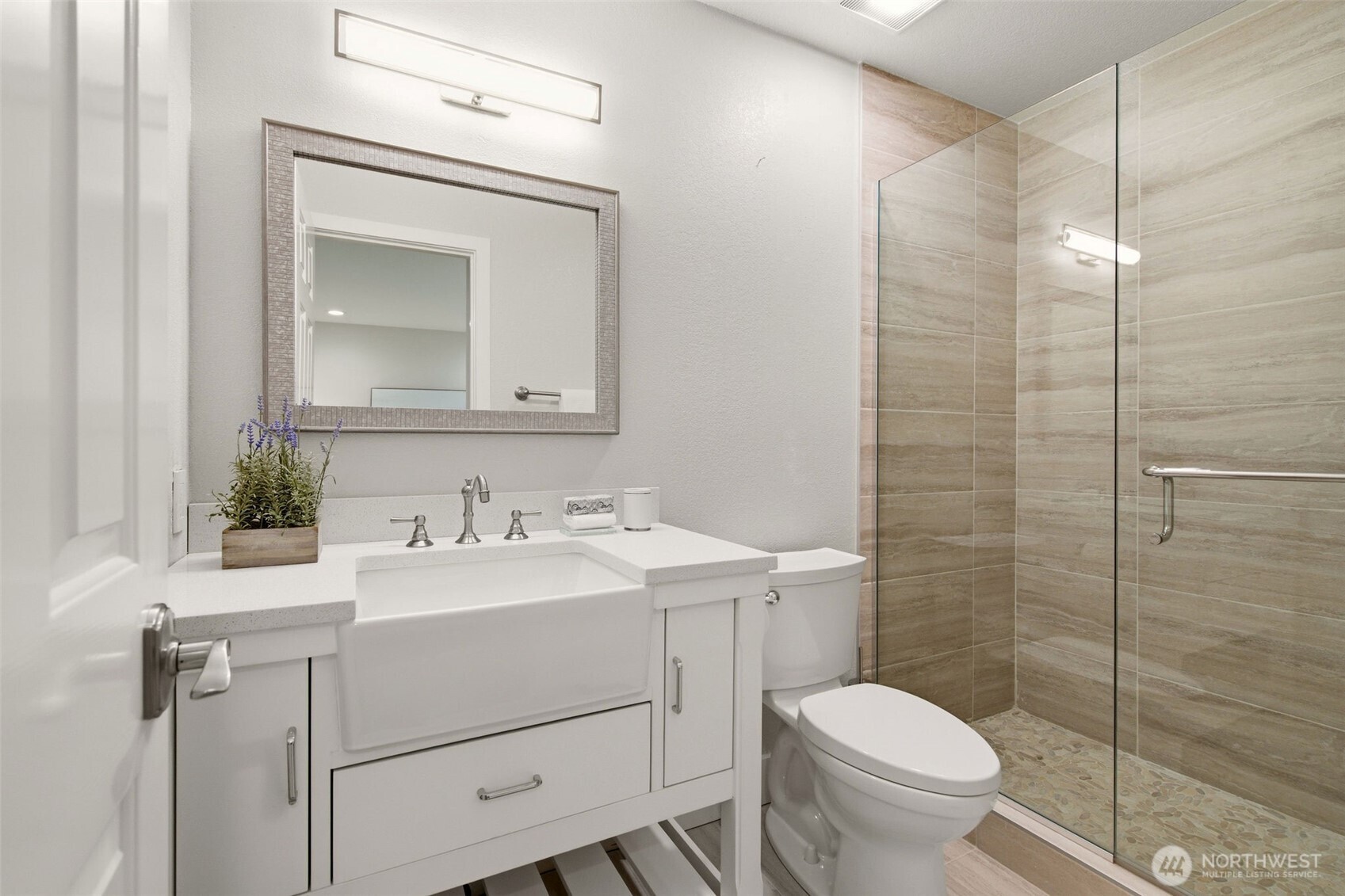 Beautifully updated bathroom with a vanity and tiled shower.