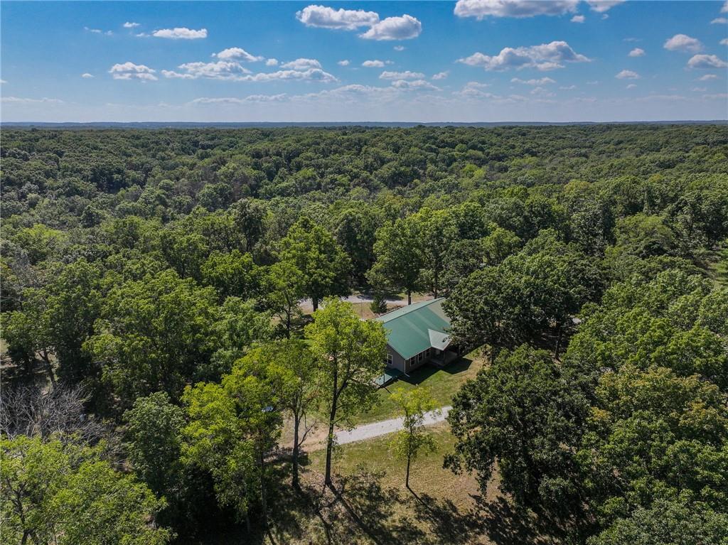Don't miss this exceptional opportunity to own a beautiful 3-bedroom, 2-bathroom home situated on 109± private acres in the peaceful countryside of Collins, Missouri. Sitting down a quiet gravel road and accessed via a long driveway, this 2,400 sq. ft. residence offers the perfect blend of comfort, seclusion, and natural beauty. Step inside to a spacious open-concept living area that effortlessly combines the kitchen, dining, and living room. At the heart of the space is a stunning  brick fireplace—perfect for cozy evenings at home. The kitchen is a chef's dream, featuring custom cabinetry, granite countertops, and a combination of tile and hardwood flooring that runs throughout the home. The generously sized primary suite offers two large closets, a luxurious en-suite bathroom with a beautifully tiled walk-in shower, and direct access to a private deck overlooking the serene backyard—ideal for enjoying your morning coffee or unwinding at sunset. The full, unfinished walk-out basement includes a built-in storm shelter and garage, offering endless possibilities for a workshop, gym, or additional storage. A 40x70 metal shop with a large lean-to provides ample space for equipment, tools, recreational vehicles, or additional parking. Whether you need room for a tractor, mower, boat, or workshop, this space is ready to accommodate your needs. The 109± acres are predominantly wooded, featuring mature hardwoods that provide excellent wildlife habitat. The property includes a wonderful food plot location and trail system, making it an ideal setting for hunting, hiking, or simply enjoying the outdoors. The land offers a perfect balance of privacy, recreation, and usability. Conveniently located just under 30 minutes from Bolivar, you'll have easy access to essential amenities including a hospital, grocery stores, and local services. Springfield is only an hour away, and Kansas City is just 1.5 hours.