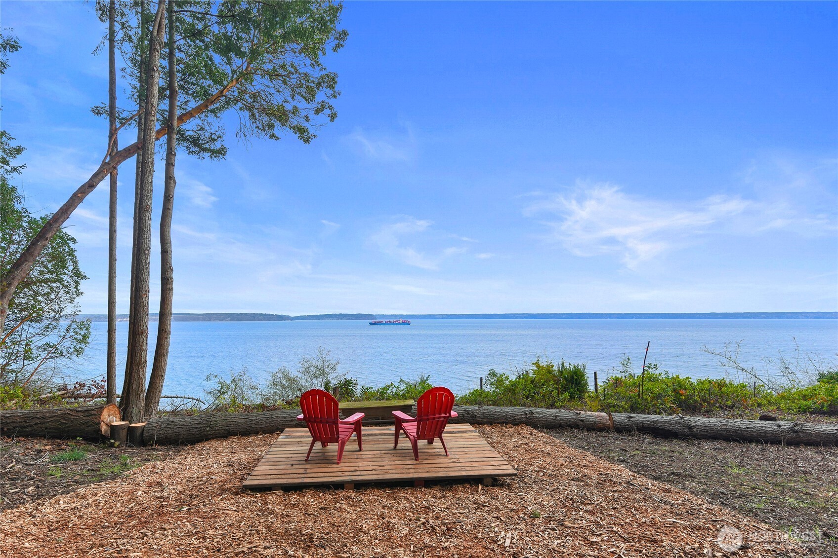 Perched above the Puget Sound on nearly 5 acres, this captivating Pan Abode retreat embodies the timeless beauty of the Pacific Northwest. The tree-lined drive opens to a sun-drenched yard where sweeping water views & tranquil surroundings set the tone for something special. The property features a detached two-car garage w/ an attached workshop & a thoughtfully updated cabin-style home that blends rustic craftsmanship w/ modern comfort. Inside, warm wood tones & expansive windows draw your gaze through the living room & kitchen to the ever-changing views of the Sound beyond. The main level offers a bedroom, mudroom/laundry area & an inviting living space anchored by a vintage wood stove, perfect for cozy NW days. High-efficiency mini splits provide year-round comfort. Step onto the new cedar entertaining deck overlooking the lawn & follow a forested path to a private viewing platform where passing ships, whales, soaring eagles & the Cascade Mountains create a living landscape that changes w/ every season. Upstairs, a second living space w/ panoramic views & deck access offers a peaceful place to unwind, alongside a full bath & a spacious primary bedroom w/ ample closet space. The adjacent parcel is also available, presenting a rare opportunity to create an almost 10-acre estate or explore ADU potential while designing your future dream home. A place where privacy, nature, and breathtaking views come together, offering not just a home, but a lifestyle few ever experience.