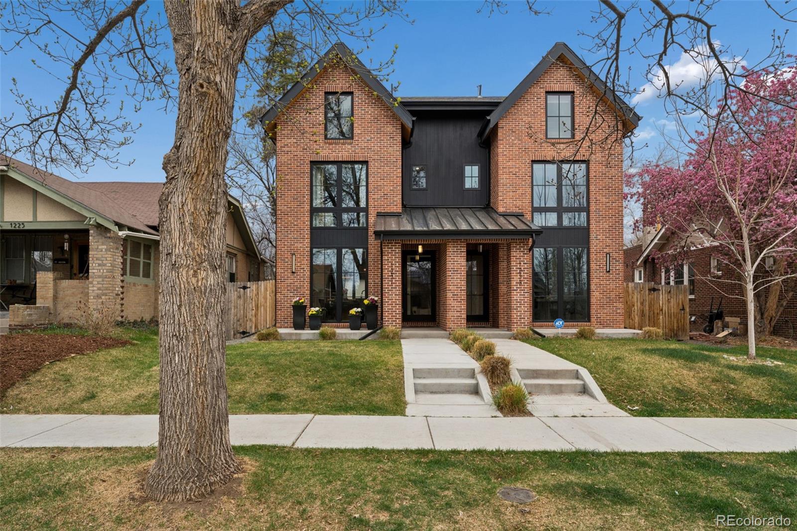 Built in 2021, this coveted south-facing duplex exudes a classic yet contemporary style, pairing a lovely brick exterior with striking black metal windows. Cross the threshold to find a home defined by fine finishes: wide-plank white oak flooring, designer lighting, and a dramatic wood floating stairway with a steel and glass partition wall. The open-concept main floor is perfectly designed for entertaining. A spacious dining room leads into the chef’s kitchen, featuring custom cabinetry, high-end stainless appliances, and a generous quartz island. The gracious family room is anchored by a gas fireplace and flows effortlessly toward the mudroom. Throughout the home, thoughtful design is on full display with excellent closet space and integrated storage solutions to keep the modern aesthetic clutter-free. Travel up the signature staircase to the romantic primary suite, a true sanctuary with a private balcony and a spa-like five-piece bath featuring a massive shower with a standing tub inside. This level also offers a second bedroom suite and a convenient laundry room. The third floor is an entertainer's dream, featuring a second family room with a wet bar, beverage fridge and a large deck—the perfect spot for a glass of wine while enjoying the sunset. The lower level completes the home with a fourth bedroom, a full bath, and a cool glass-walled office/flex space. The private backyard leads to an oversized detached 2-car garage, finished with drywall and shelving for ample storage. The location is simply unbeatable: you are just two blocks from neighborhood favorites like Blue Pan Pizza, Bamboo Sushi, and Sienna Wine Bar. Nature is at your doorstep with City Park (1/2 mile), Congress Park (3/4 mile), and Cheesman Park (1 mile) all within reach, and the premier shopping of Cherry Creek is just a 5-minute drive away. This is urban living at its finest!