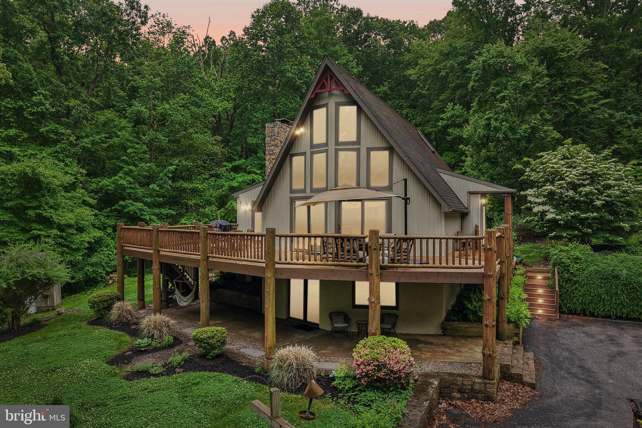 Welcome to a gorgeous, resort-like retreat and true nature lover’s dream escape. This stunning 3-bedroom, 3-bath home offers privacy, comfort, and effortless indoor-outdoor living, all surrounded by peaceful wooded views.The open-concept living and dining area features soaring cathedral ceilings, polished floors, and expansive windows that flood the space with natural light. A wrap-around deck overlooks the surrounding woods and creates an ideal setting for relaxing, entertaining, or taking in the tranquil natural surroundings. Beneath the deck, covered patio spaces offer shaded areas perfect for lounging, with room for a hammock, seating, and peaceful moments immersed in nature.The fully equipped kitchen flows seamlessly into both indoor and outdoor dining areas, making hosting easy and inviting. Three bedrooms are thoughtfully arranged across multiple levels for added privacy, each enhanced with newly added split units for year-round comfort. A lower-level lounge with a cozy wood-burning stove provides a welcoming space to unwind.Additional highlights include a detached two-car garage with finished loft space ideal for entertaining or flexible use, a seasonal saltwater pool, and a fire pit for memorable evenings under the stars. Located just 18 miles from Spring Mountain skiing, this exceptional property blends serene retreat living with access to year-round recreation.A rare opportunity to own a truly special escape—perfect as a full-time residence, weekend getaway, or investment property.Mortgage savings may be available for buyers of this listing.