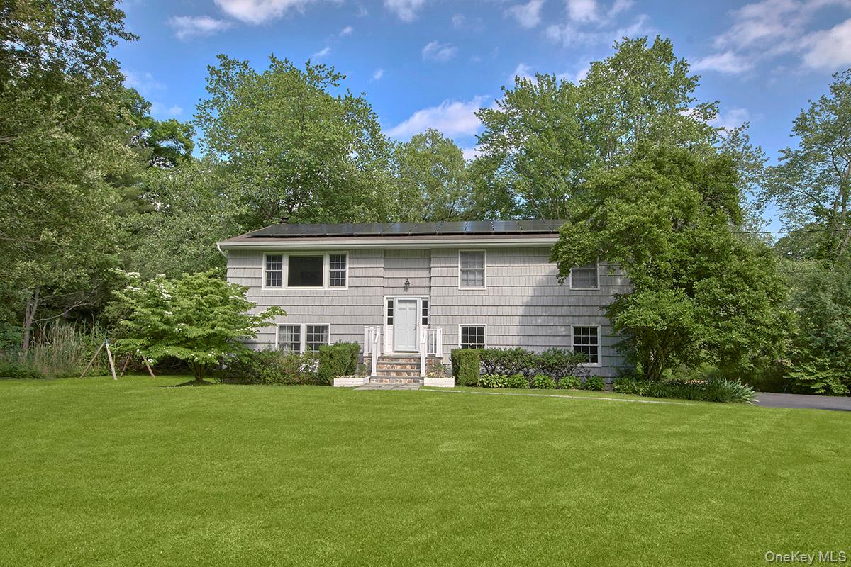 Set on a level .64-acre property along one of Chappaqua's most sought-after neighborhood streets, 9 Oak Hill Road is a beautifully updated 4-bedroom, 3-bath Raised Ranch that offers spacious, light-filled living in a peaceful natural setting. A covered front porch welcomes you into an entry foyer, where a short mezzanine staircase leads to the main living level. Here, a gracious living room with a picture window flows effortlessly into the adjoining dining room, creating an inviting space for everyday living and entertaining. Adjacent to the dining room, the eat-in kitchen completes the home's open, functional layout. Oversized windows at both the front and rear fill the living areas with natural light, while the property's exceptional setting—backing to the Saw Mill River Audubon Society's Cameron-Murfeldt Sanctuary—offers privacy, scenic views, and a charming pond that enhances the tranquil landscape.The eat-in kitchen is thoughtfully designed with white cabinetry, stainless steel appliances, a picture window, and a sun-filled breakfast area that enjoys morning light. A door opens directly to the deck, making outdoor dining and weekend barbecues effortless.Three well-proportioned bedrooms are located on the main level, including a spacious primary suite with two closets and a private bath. A corner bedroom enjoys windows on two sides, while the third bedroom features two front-facing windows and a generous double closet. Every bedroom in the home is outfitted with custom California Closets, providing beautifully designed, highly functional storage and organization.The finished walk-out lower level provides exceptional additional living space with a generously sized family room featuring hardwood floors, a decorative electric fireplace, and sliding glass doors that open to the patio. A private, expansive fourth bedroom with hardwood floors and a double closet, a full bath with shower, laundry area, utility room, abundant storage, and direct access to the attached two-car garage complete this versatile level. Set back from the road with a level driveway and expansive front lawn, this inviting home offers the perfect balance of comfortable living, effortless entertaining, and the peaceful beauty of its park-like surroundings.