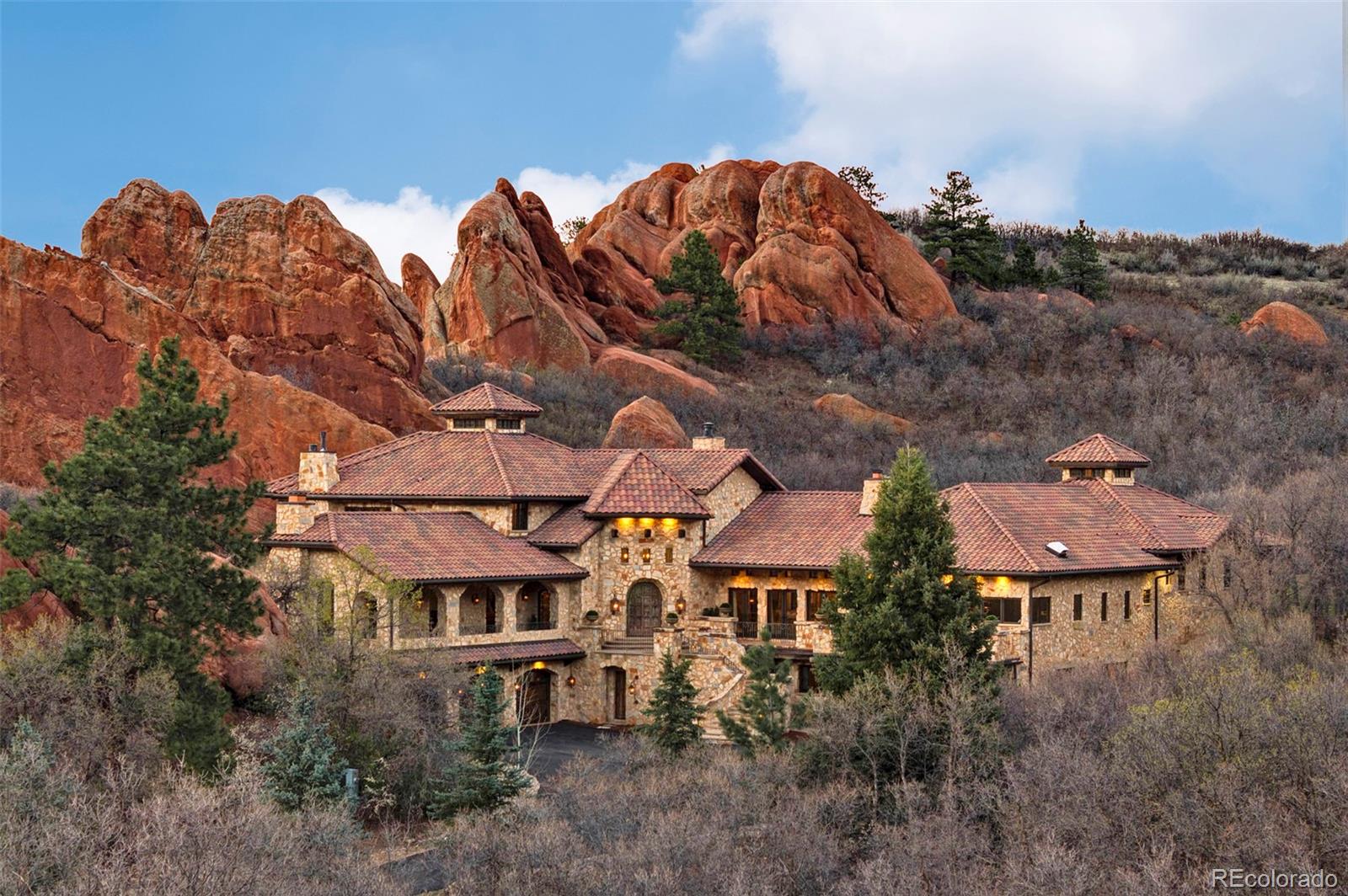 Set within the breathtaking landscape of Roxborough State Park and bordered by the untouched beauty of Pike National Forest, this extraordinary $8.4M custom estate offers a rare fusion of European elegance and Colorado’s rugged natural splendor.Thoughtfully designed with timeless Italian inspiration, the home is masterfully constructed with a full limestone exterior, copper gutters, and artisan-crafted details that blend seamlessly into the dramatic red rock outcroppings across two parcels totaling eight private acres. The main residence sits on a 3-acre homesite, while a separate 5-acre parcel directly across the road features dual gated entries and a substantial four-car garage/workshop.Inside, the residence offers seven bedroom suites, each with en-suite baths, for a total of ten bathrooms. Rich textures of mixed-species wood flooring, brick, and limestone tile create a warm yet refined aesthetic, complemented by reclaimed wood beams from Denver’s historic Ice House. The kitchen is a true showpiece, appointed with dual Sub-Zero refrigerators & dishwashers, a Wolf range with double ovens, steam oven, warming drawer, beverage refrigerator, & striking dual copper sinks.The primary suite serves as a private retreat, complete with dual closets, sitting room, kitchenette/sunroom, and a secluded covered patio. The spa-like bath features a copper soaking tub & steam shower.Additional highlights include a theater room, multiple offices and flexible living spaces, three laundry areas, and a dog washing station. Bespoke ironwork, copper accents, antique elements, and stained glass details enhance the home’s character.Outdoor living is equally captivating, with 3 lookout areas built into the red rock formations, offering panoramic views.  There is also a seasonal creek flowing through the property from April to July.With geothermal HVAC and reverse osmosis systems,this is a legacy estate where timeless European craftsmanship meets the iconic beauty of Colorado.