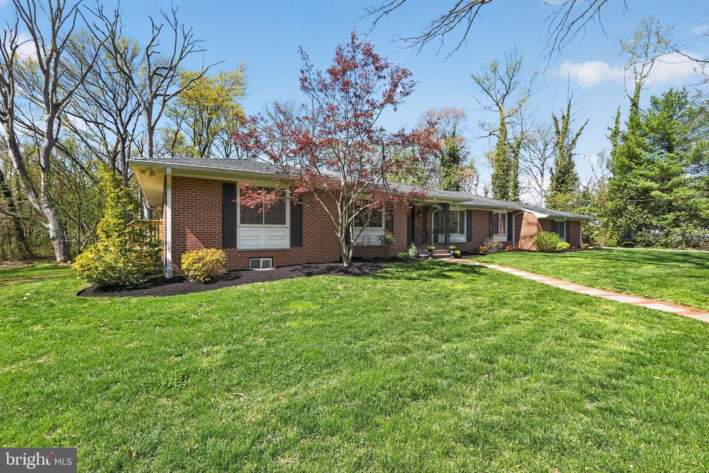 Tucked at the end of a quiet street in Moorestown, this expansive brick ranch offers a rare sense of privacy on 1.37 acres surrounded by mature trees and established landscaping. With 5 bedrooms, 3 full bathrooms, a 2 car attached garage, and a six plus car concrete driveway, the property provides both space and ease in a setting that feels quietly removed. A welcoming approach begins with a slate walkway bordered by brick, leading to a covered porch and entry finished in slate. Inside, hardwood flooring extends throughout the main living areas and bedrooms, complemented by natural light that moves easily from room to room. The formal living and dining room combination is defined by natural light spilling onto the dental molding and classic cylindrical columns, creating a subtle architectural transition into the kitchen and family room beyond. The family room offers a comfortable gathering space centered around a stone wood burning fireplace with built in bookshelves on either side. Large picture windows frame views of the rear yard, bringing the outside in, while recessed lighting adds a soft, balanced ambiance. A glass door from the family room extends the space outward, inviting natural light and offering a quiet connection to the rear yard. The kitchen features tile flooring, granite countertops, stainless steel appliances, and a functional layout with a breakfast bar that remains open to the family room. Just beyond, the mudroom is both practical and well appointed, offering a wet sink, additional cabinetry, and access to the garage. This area also leads to a versatile bonus room that serves as the fifth bedroom, office, or private retreat. The adjoining sunroom, lined with windows, provides a quiet place to take in the surrounding landscape through every season. The primary suite includes hardwood flooring, double closets with organizers, private side yard access, a double vanity, and a stall shower. The remaining bedrooms are generously sized, each offering two closets with built in organizers for exceptional storage. An updated hall bathroom offers a double vanity and tub and shower combination, while a third full bathroom with a stall shower is positioned near the sunroom for added convenience. A full unfinished walk out basement, naturally divided into four sections, offers substantial space and flexibility, presenting a unique opportunity to tailor the lower level to a range of uses depending on a buyer’s needs and vision. A shed, conveniently located just off the driveway, provides additional storage for outdoor equipment. Set within one of Moorestown’s most established settings, this property offers a sense of quiet separation while remaining within reach of everyday needs. Approximately 20 minutes to Philadelphia, 35 minutes to Trenton, and convenient to major roadways, the location also offers easy access to local restaurants and shopping. For travel north, Hamilton Station is within reach and provides direct rail service to New York City and beyond. The location is also close to local parks and walking trails, offering a natural extension of the setting beyond the property itself.