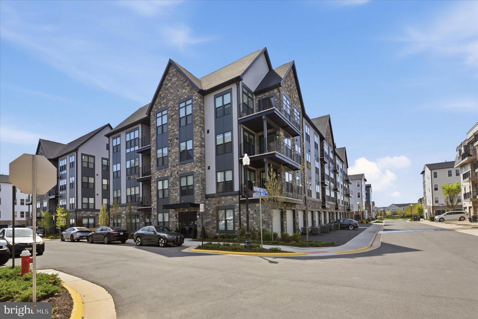Step into easy, elevated living in this beautifully appointed - barely lived in (5 weeks)-  3rd-floor condo in Archer Square Condominiums in Birchwood at Brambleton, where thoughtful design, stylish finishes, and exceptional amenities come together. 1 Bedroom PLUS  den, 2 bathroom home! The open-concept unit with LVP flooring throughout, features a well-designed kitchen with quartz countertops, stainless steel appliances, an oversized island with breakfast bar seating and pendant lighting(3), plus abundant storage. The adjacent dining area has a sliding glass door to the private balcony, creating an inviting spot for morning coffee or relaxing afternoons. The spacious living room features luxury electronic window shades and a ceiling fan. Relax in the primary bedroom, which offers a walk-in closet, more luxury electronic shades, and ceiling fan. The primary bath is designed for comfort with dual sinks, a large shower with built-in bench, and additional storage cabinets. A versatile den with closet and ceiling fan provides flexible space for an office, reading area, or additional living space, while a second full bath with tub/shower serves guests. Finally, a washer and dryer are conveniently located in the unit. Outside, the home includes a one-car garage with driveway parking. The Residents of Archer Square, a vibrant 55+ community, enjoy an impressive array of amenities, including an indoor and outdoor pool, exercise room, community center, game room, art studio, lake, secure building entry with elevator access, and so much more! With its combination of low-maintenance living, attractive finishes, private outdoor space, garage parking, and resort-style community amenities, this condo offers a comfortable place to settle in and enjoy all that Brambleton has to offer. Don't forget the full builder warranty that conveys !! Open House: Sat 8/29 from 1-3pm