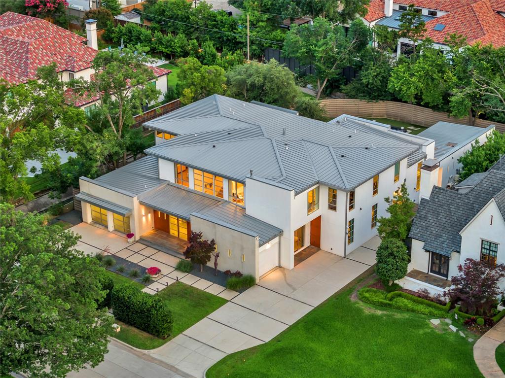 In the heart of the Fairway of Preston Hollow, this striking modernist home blends architectural drama with everyday comfort. Designed for both lively entertaining and relaxed family living, its open, light-filled spaces flow effortlessly to the outdoors. Retractable screens create a seamless extension of the main level, opening to 800+ square feet of covered living space. A second outdoor lounge channels mid-century charm with a fire pit beside a striking $400K negative edge pool, hot tub, and tanning shelf—set against a lush, turfed play yard. Inside, soaring ceilings with exposed steel beams and custom finishes define the expansive main level, where a serene primary suite and media room offer retreat. Upstairs, four bedrooms surround a central living area with balcony and bar, while two flex spaces—including a gym with laundry—adapt to any lifestyle. Three-car garage and standing seam metal roof. With a Control4 system, elevator and climate-controlled wine room, this home is turnkey luxury ready for immediate occupancy.