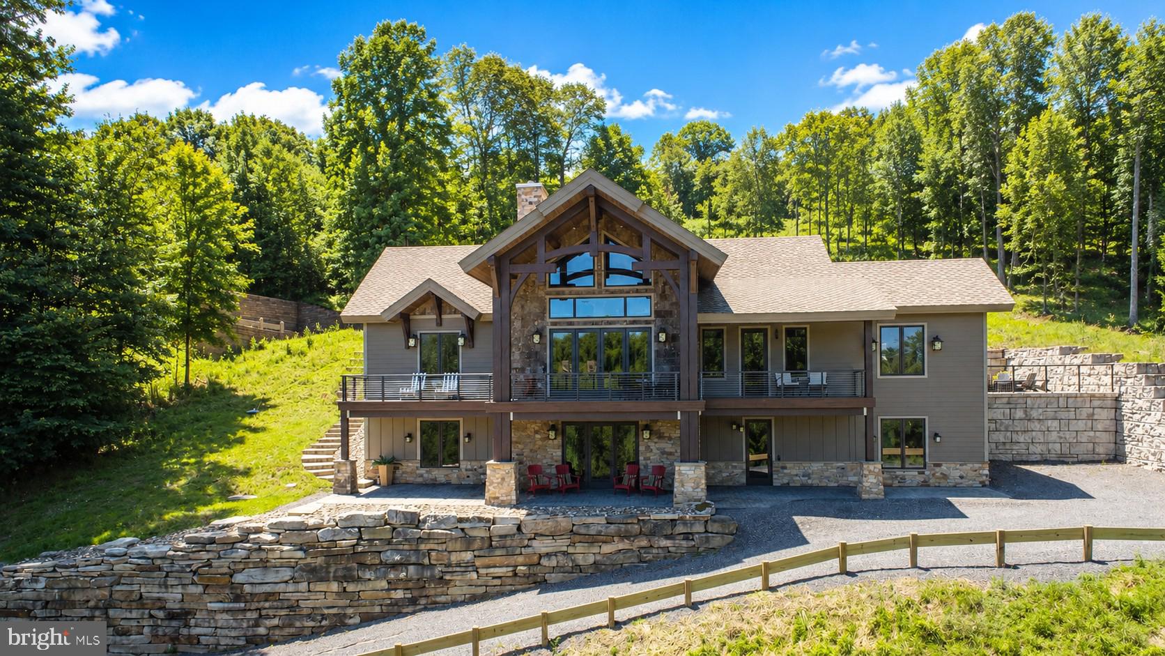 Completed in 2020, this extraordinary custom-built Deep Creek Lake retreat offers the perfect blend of luxury craftsmanship, year-round recreation, and breathtaking lake views! Ideally situated just minutes from Wisp Resort and accompanied by nearby lake access with a dedicated boat slip, this exceptional vacation home is designed for both entertaining and relaxing in every season.Featuring four spacious bedroom suites, each with its own private full bath, plus two additional half baths, the home delivers comfort and privacy for family and guests alike. Thoughtfully designed with custom Douglas Fir timbers, tongue-and-groove ceilings, live-edge wood details, and premium finishes throughout, every space showcases exceptional attention to detail.The main living areas are highlighted by soaring ceilings reaching over 24 feet, dramatic walls of glass framing expansive lake views, and stunning natural stone fireplaces with Mendota gas inserts. The gourmet kitchen is a showpiece, featuring an oversized quartz island, custom cabinetry, farmhouse copper sink, induction cooktop, double convection ovens, pantry, marble breakfast/game table, and GE appliances.Luxury continues throughout the home with heated concrete flooring, custom wood flooring, Anderson windows and doors, tankless hot water, remote-controlled Honeywell HVAC, extensive designer lighting, and structural insulated panel construction for superior energy efficiency. Each bedroom suite offers its own unique character with custom cabinetry, upscale tile work, vessel sinks, glass shower enclosures, and spa-inspired finishes. The primary suite features distressed cobblestone flooring, ledger stone accents, dual LaCava sinks, and a luxurious honed travertine shower.Outdoor living is equally impressive with Trex decking, custom stone patios, natural bark siding, a custom 7-foot gas fire pit, and gas grill/generator readiness. Whether enjoying lake views from the deck, spending the day on the water from your nearby boat slip, or skiing just minutes away at Wisp Resort, this property offers an unparalleled Deep Creek Lake lifestyle.Additional premium features include Hardie Plank and natural stone exterior accents, IKO Armourshake roofing, custom cabinetry throughout, open-riser staircase with cable railings, custom fireplaces and built-ins, a second dishwasher, dedicated office space, and public water and sewer.A rare opportunity to own a one-of-a-kind luxury lake home where exceptional craftsmanship, modern amenities, and four-season recreation come together in one remarkable setting!
